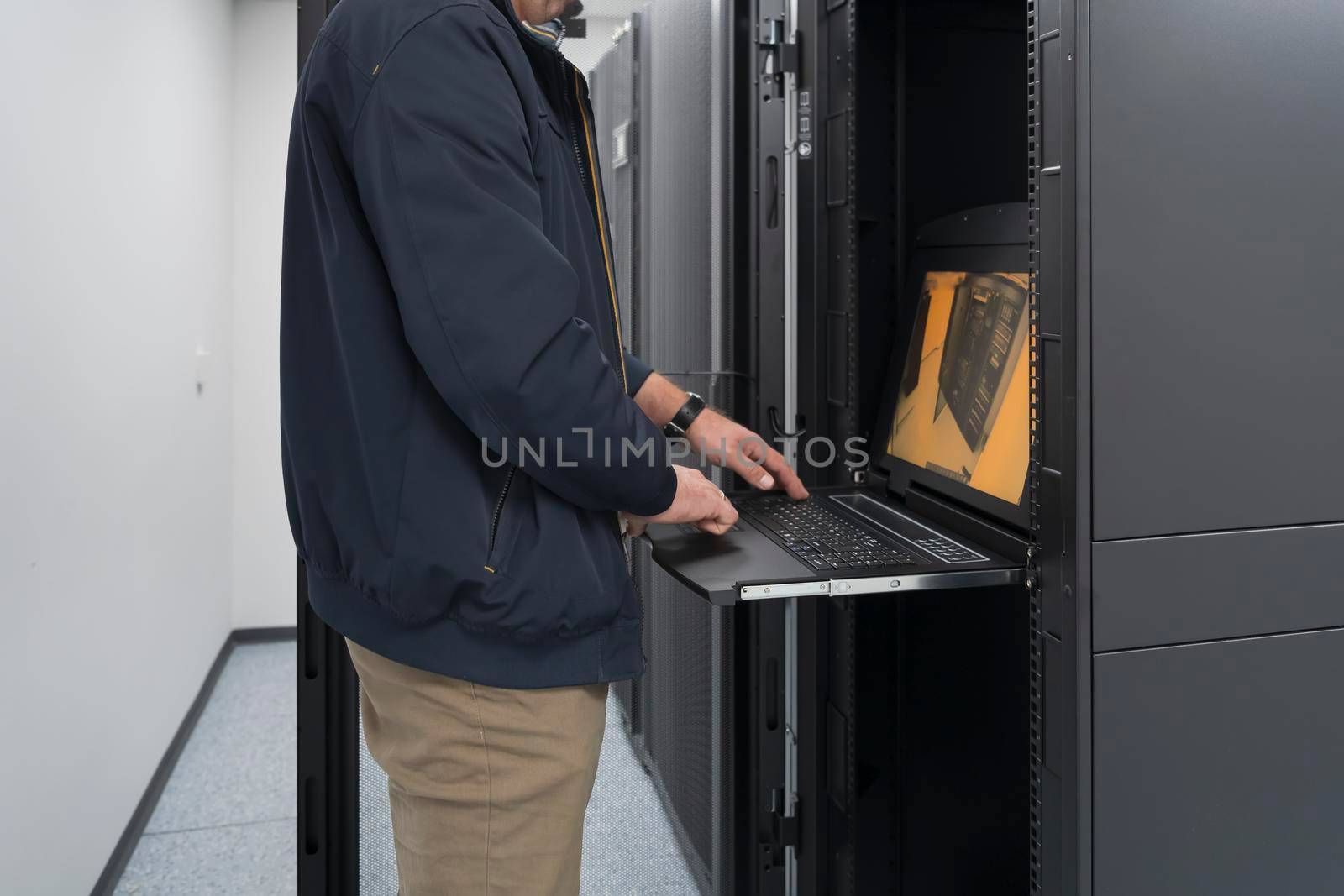 Close up on Data Center Engineer hands Using keyboard on a supercomputer Server Room Specialist Facility with Male System Administrator Working with Data Protection Network for Cyber Security. by dotshock