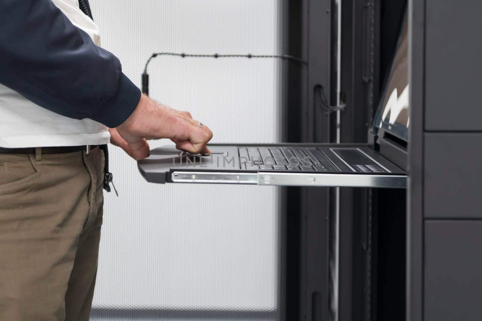 Close up on Data Center Engineer hands Using keyboard on a supercomputer Server Room Specialist Facility with Male System Administrator Working with Data Protection Network for Cyber Security. by dotshock