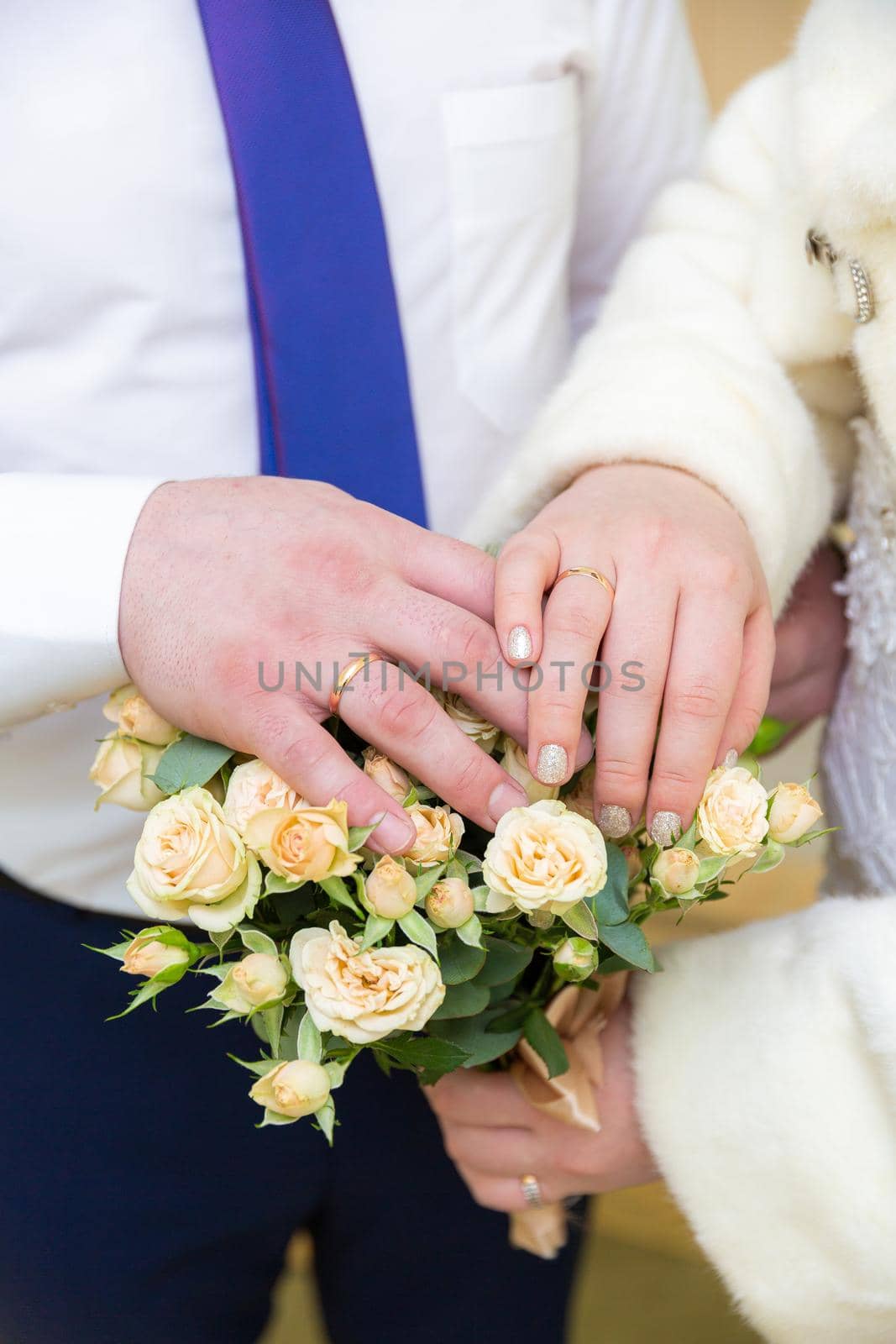 The hands of the newlyweds hold flowers. High quality photo