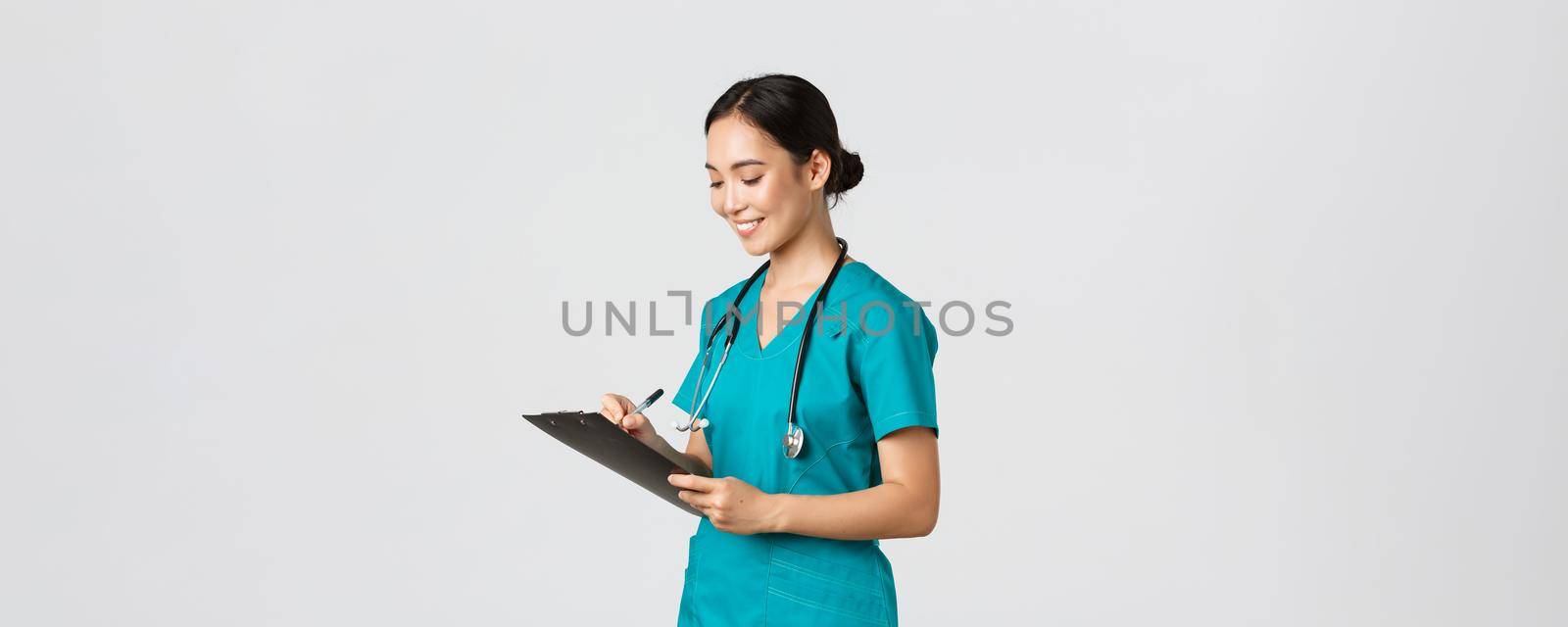 Healthcare workers, preventing virus, quarantine campaign concept. Beautiful smiling asian doctor, nurse running checkup in hospital, looking at clipboard with patient results, examine people.