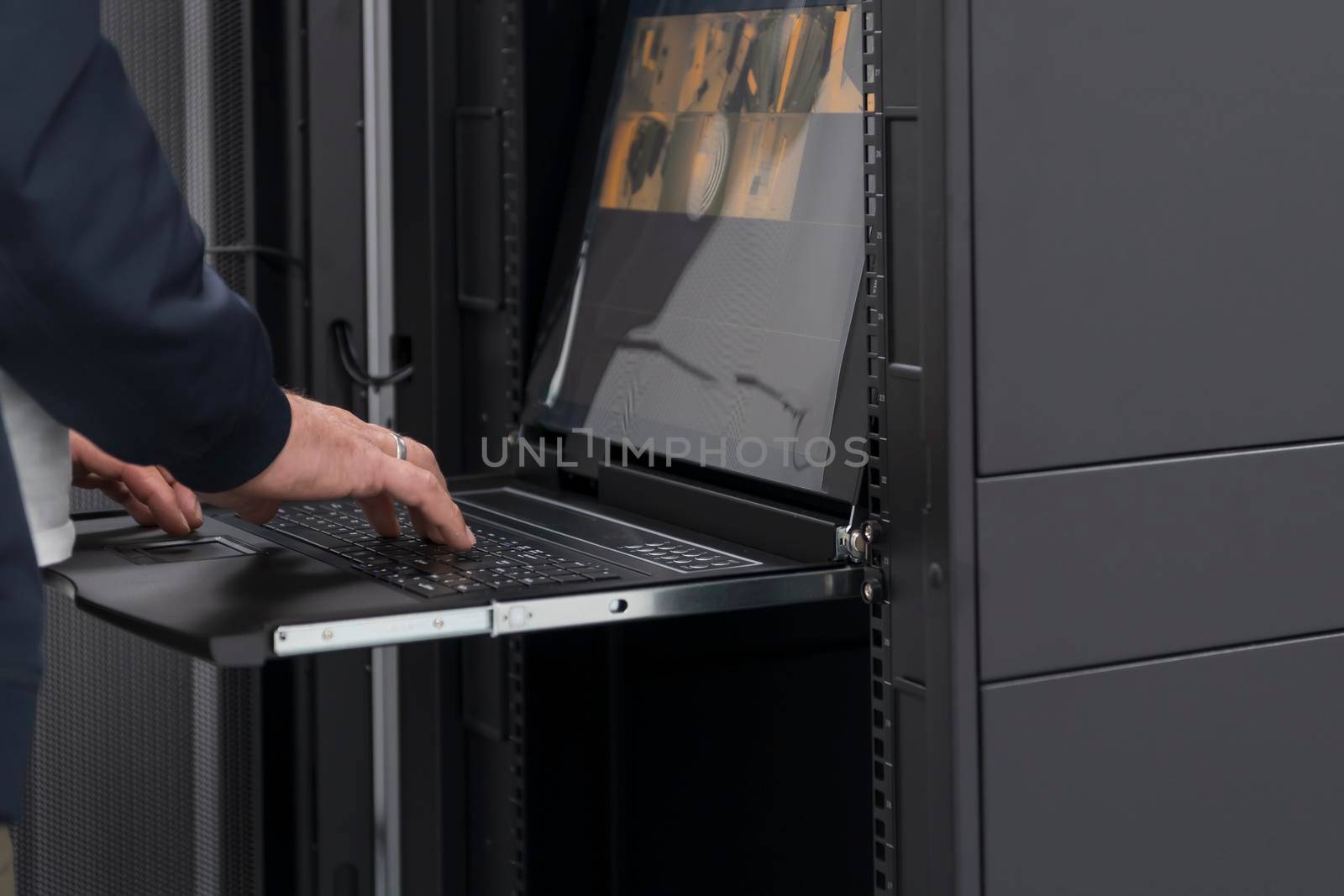 Close up on Data Center Engineer hands Using keyboard on a supercomputer. Server Room Specialist Facility with Male System Administrator Working with Data Protection Network for Cyber Security.