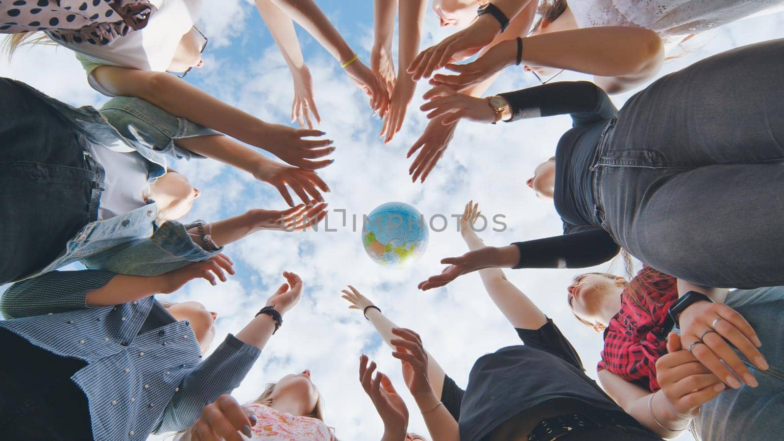 Female student girls standing in a circle toss the world globe up