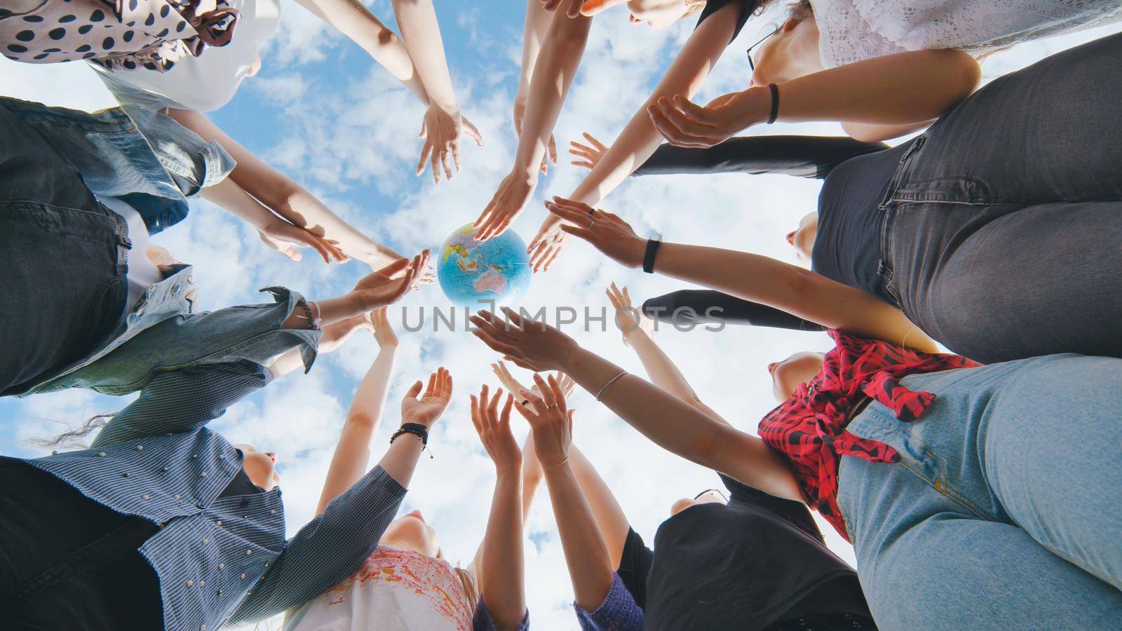 Female student girls standing in a circle toss the world globe up. by DovidPro