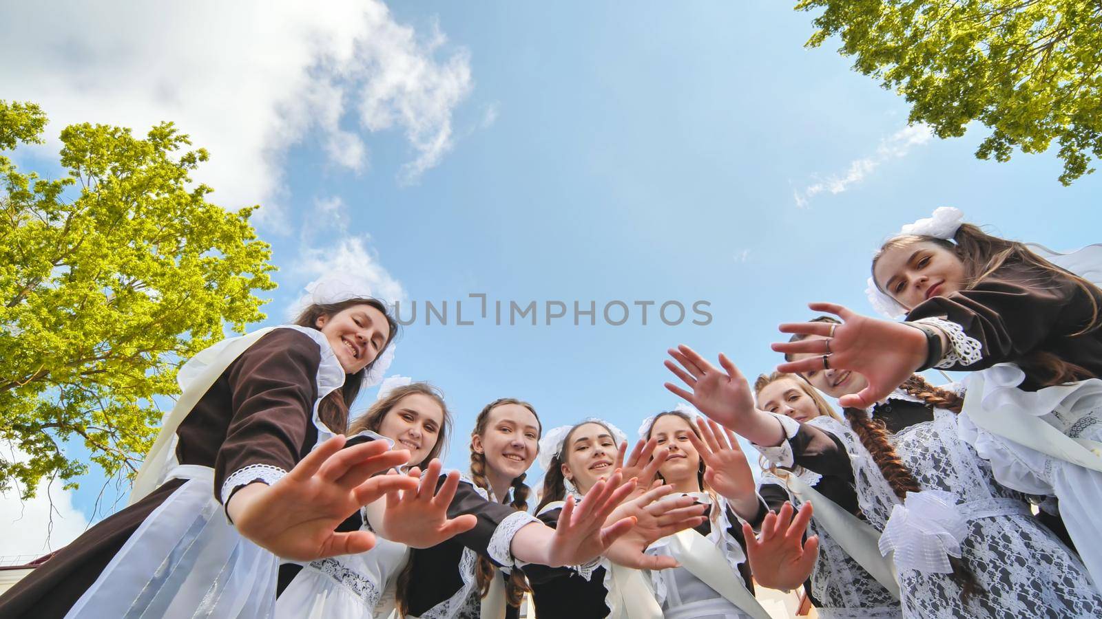 Happy Russian school graduates are stretching their hands on their last school day. by DovidPro