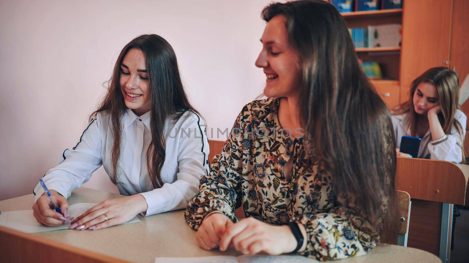 Students in the classroom at their desks in front of the're coming out. by DovidPro