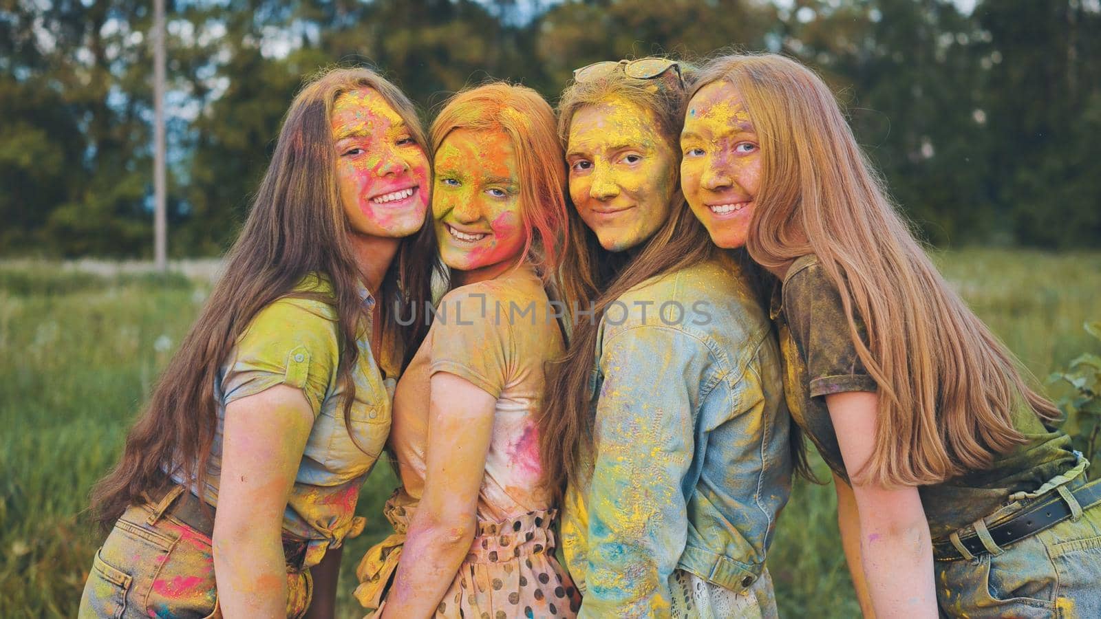 Cheerful girls posing smeared in multi-colored powder