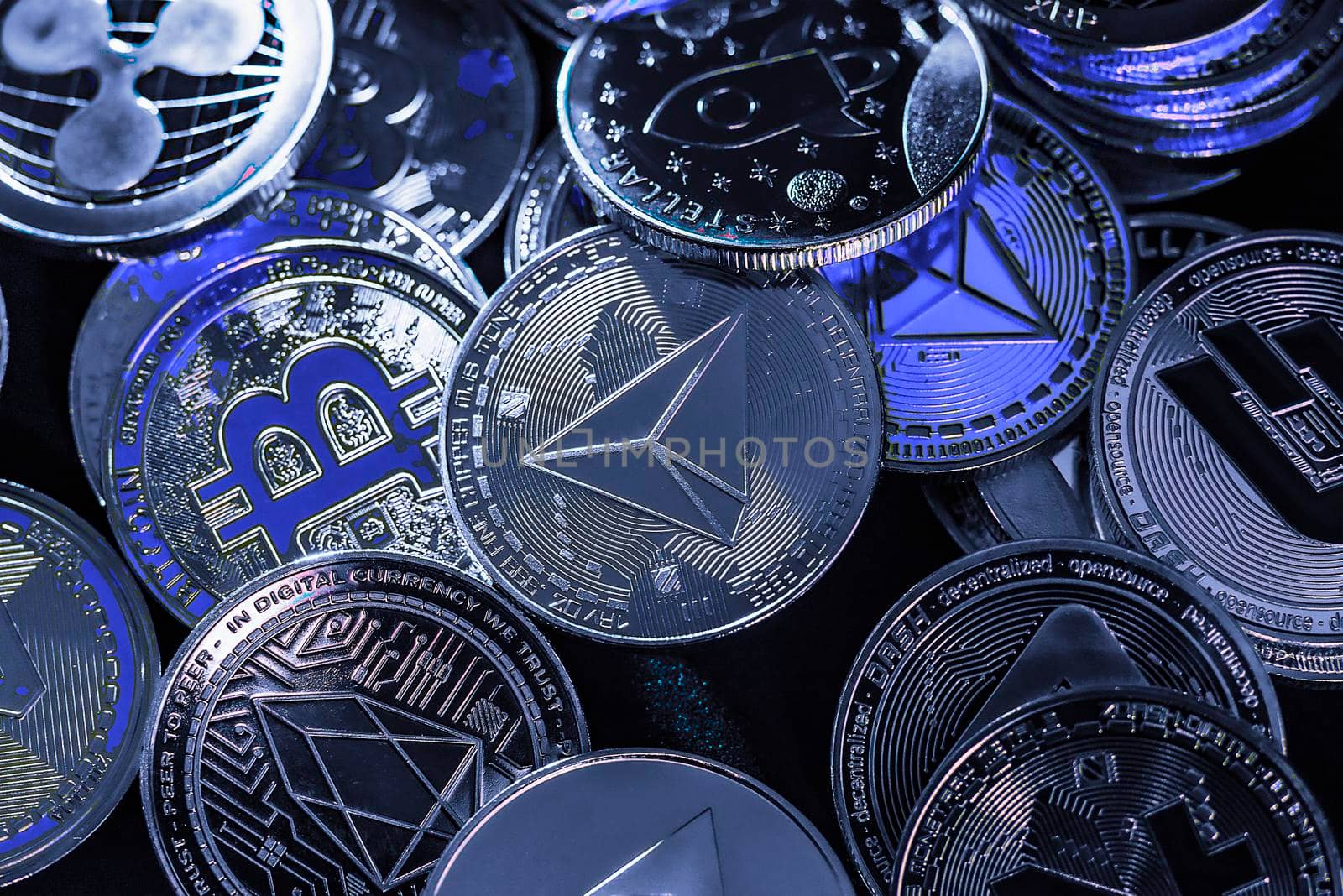 Horizontal view of cryptocurrency tokens, including Bitcoin, Tron, and Dash saw from above on a black background. High quality photo