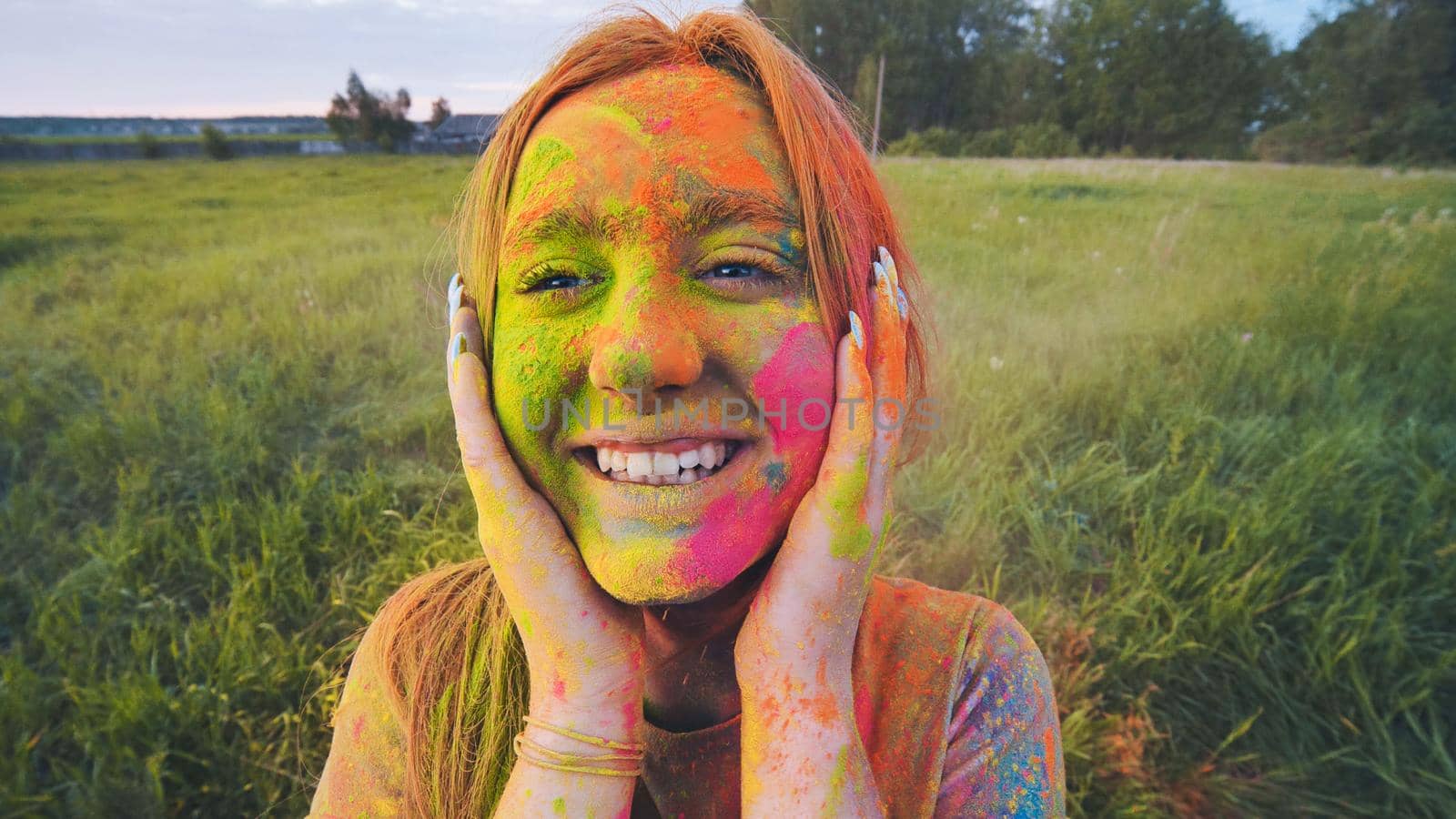 Cheerful girl posing smeared in multi-colored powder. Close-up face