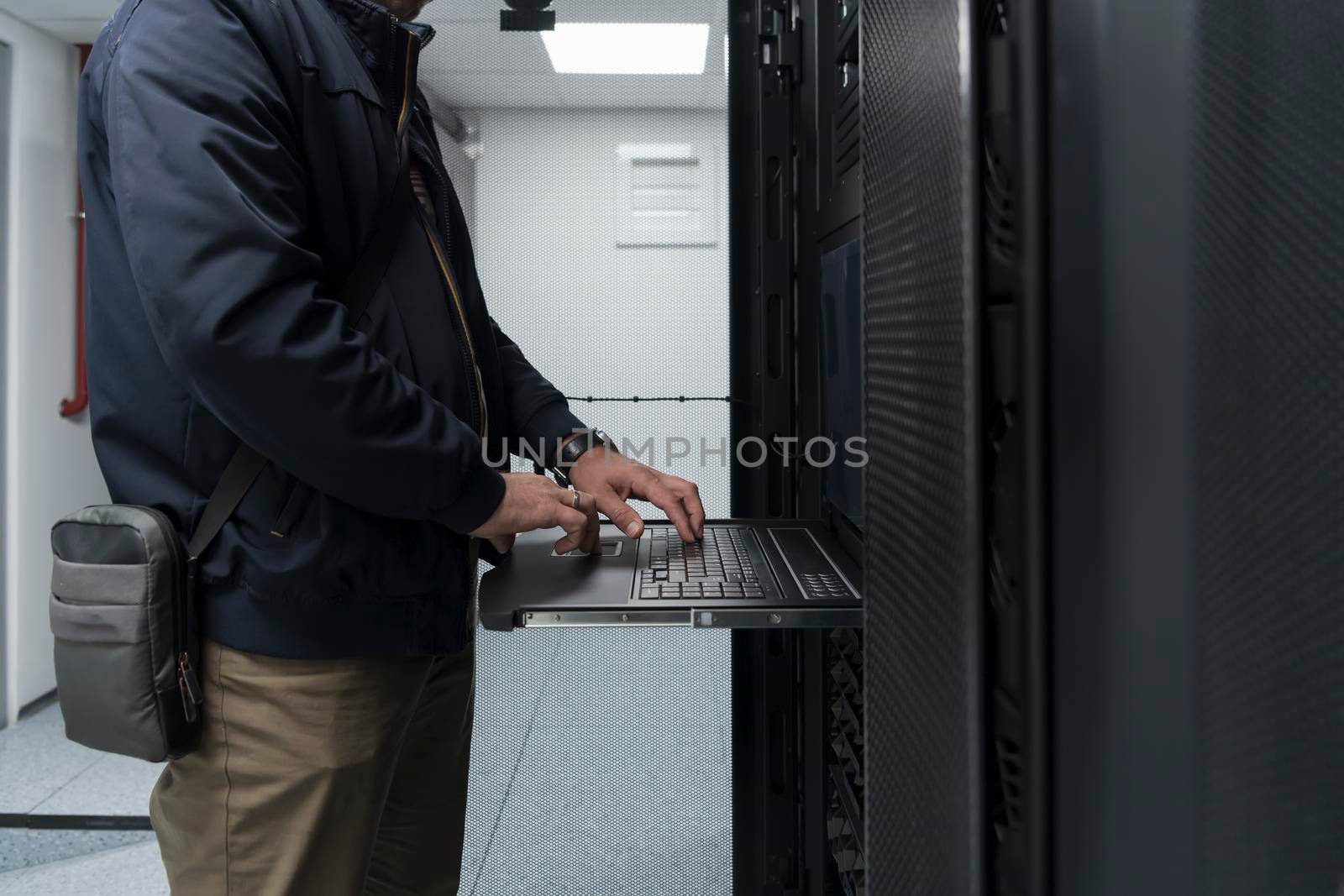 Close up on Data Center Engineer hands Using keyboard on a supercomputer. Server Room Specialist Facility with Male System Administrator Working with Data Protection Network for Cyber Security.