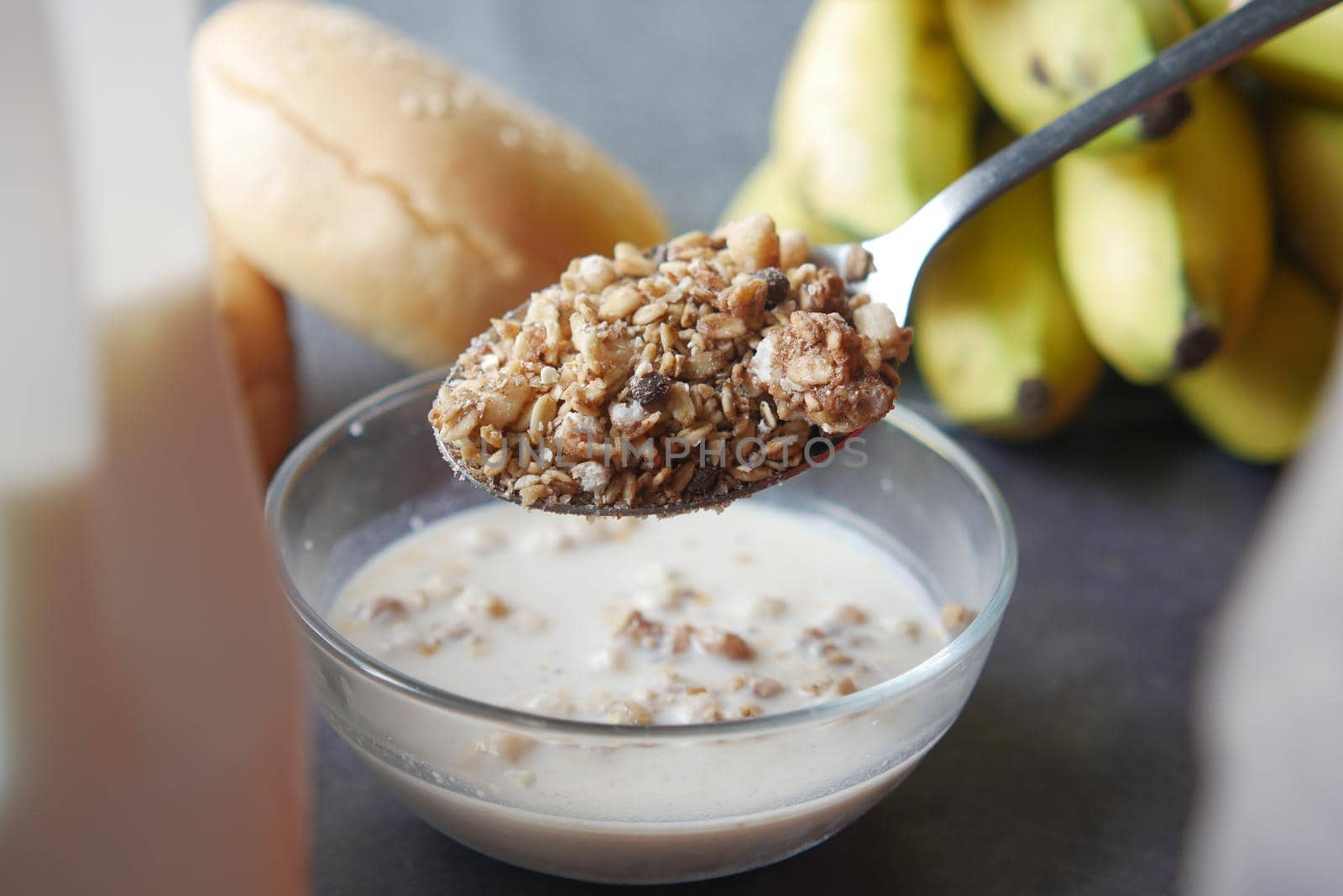 putting musli in a bowl full of milk on table .