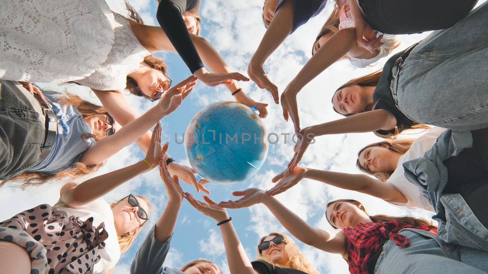 Earth conservation concept. 11 girls surround the rotating earth globe with their palms hands. by DovidPro