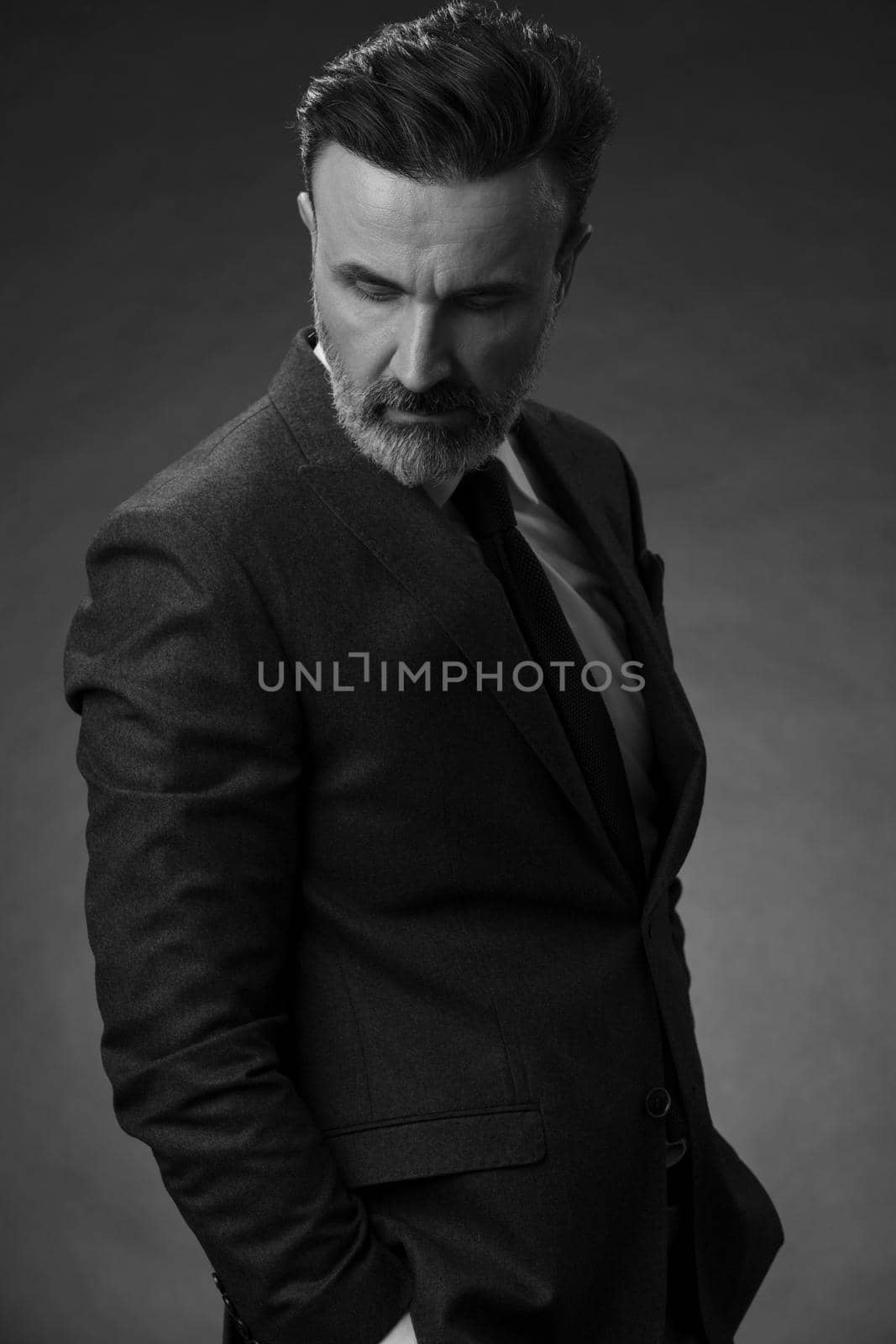 Portrait of a stylish elegant senior businessman with a beard and casual business clothes in photo studio isolated on dark background gesturing with hands by dotshock