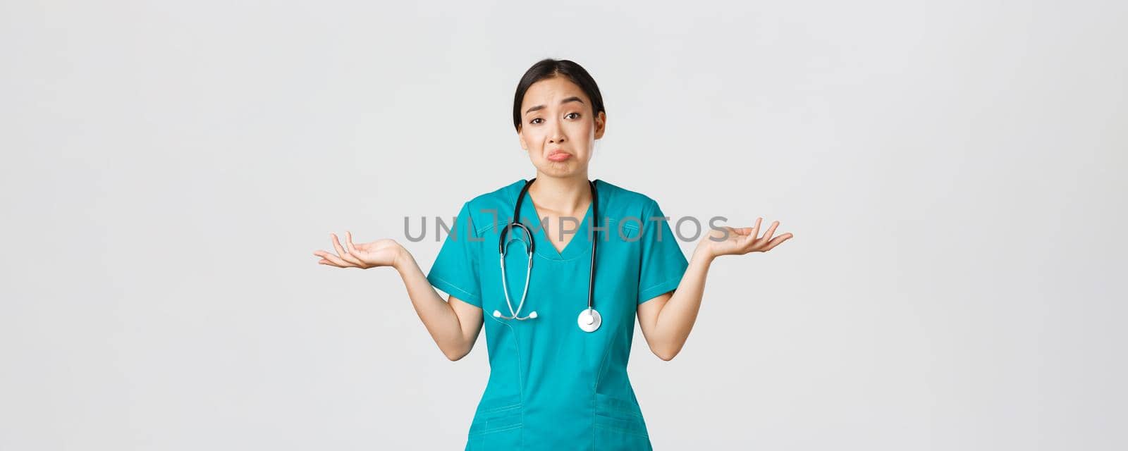 Covid-19, healthcare workers, pandemic concept. Portrait of clueless asian female nurse, woman doctor shrugging and spread hands sideways unaware, dont know, cant help, white background by Benzoix