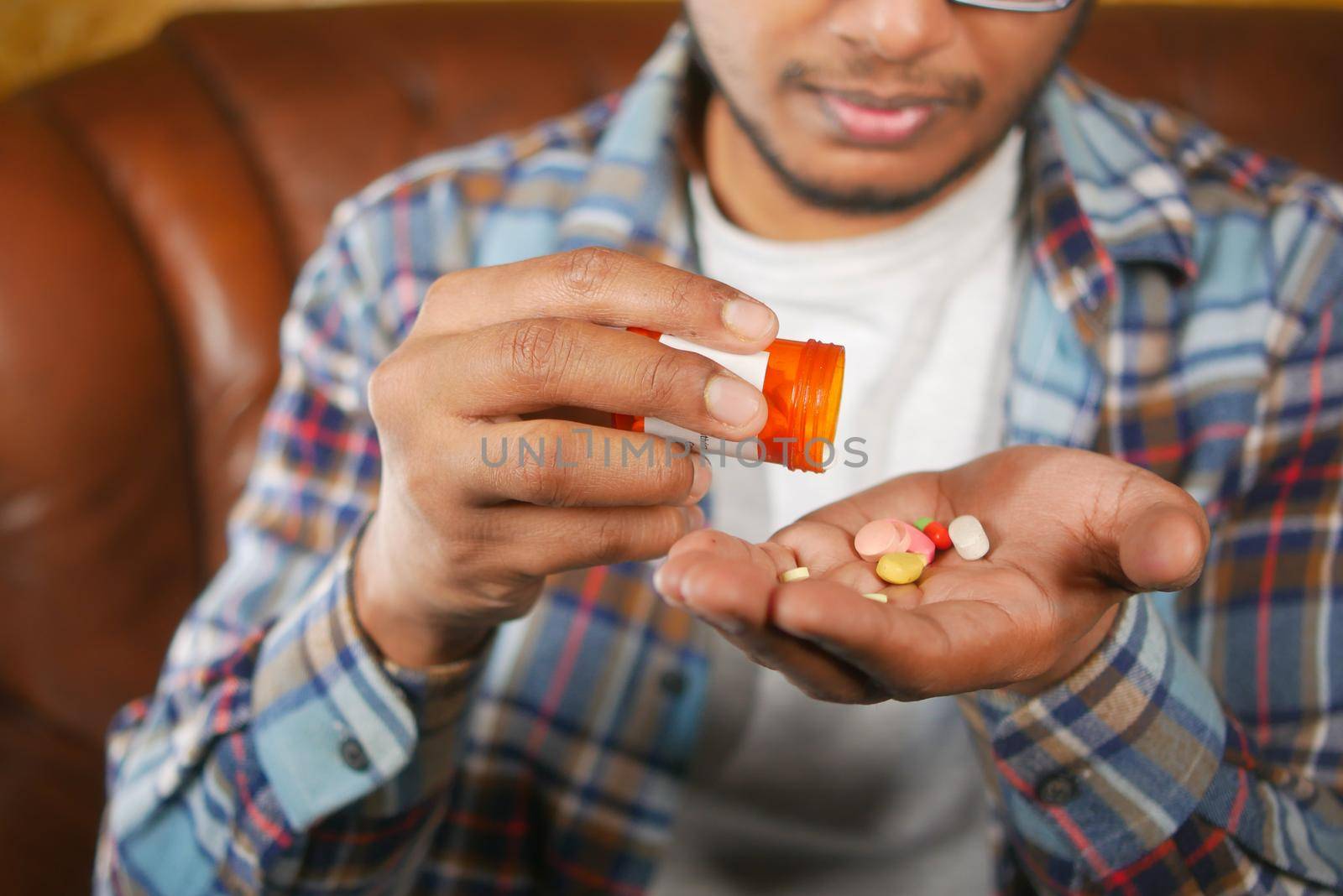 man's hand with pills spilled out of the container .