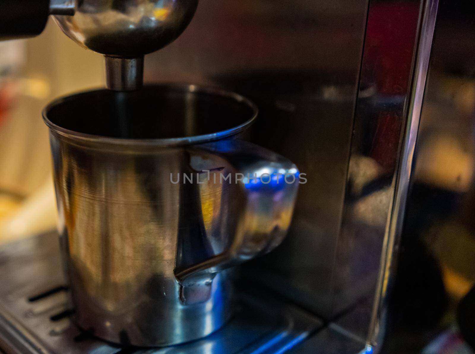 Close-up of large metal cup ready to be filled on espresso machine. Shiny steel mug on professional coffee machine. Caffeine and drink preparation