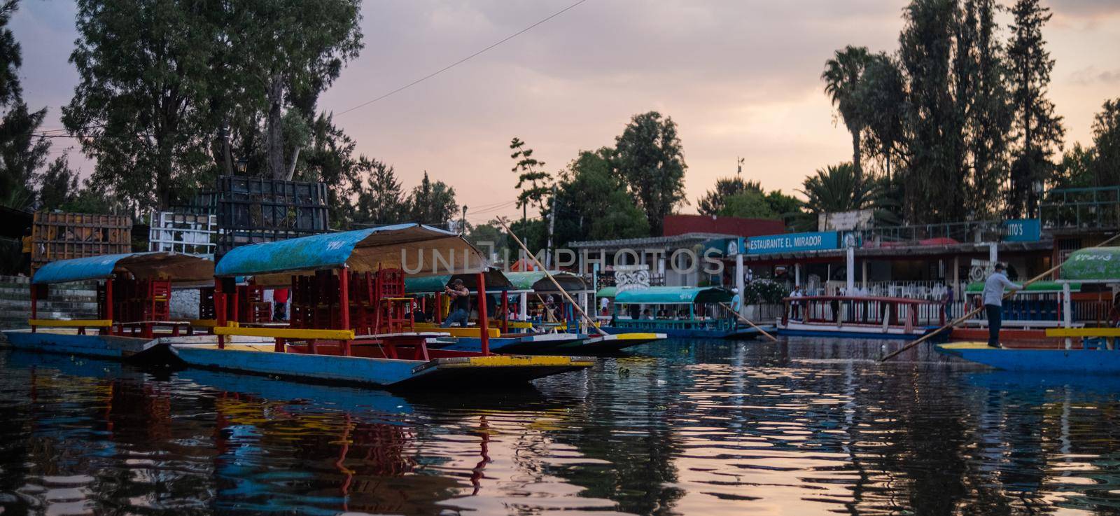 Traditional colorful trajineras in Xochimilco lake under beautiful sky by Kanelbulle