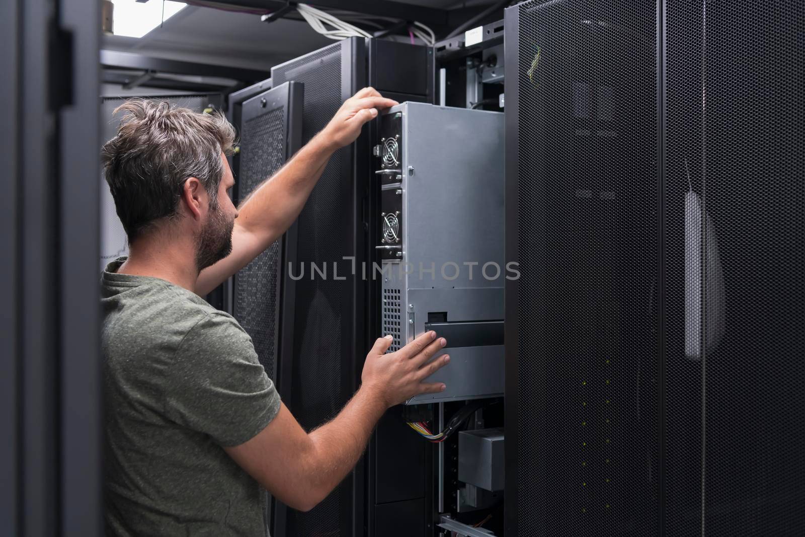 IT engineer working In the server room or data center. The technician puts in a rack a new server of corporate business mainframe supercomputer or cryptocurrency mining farm.