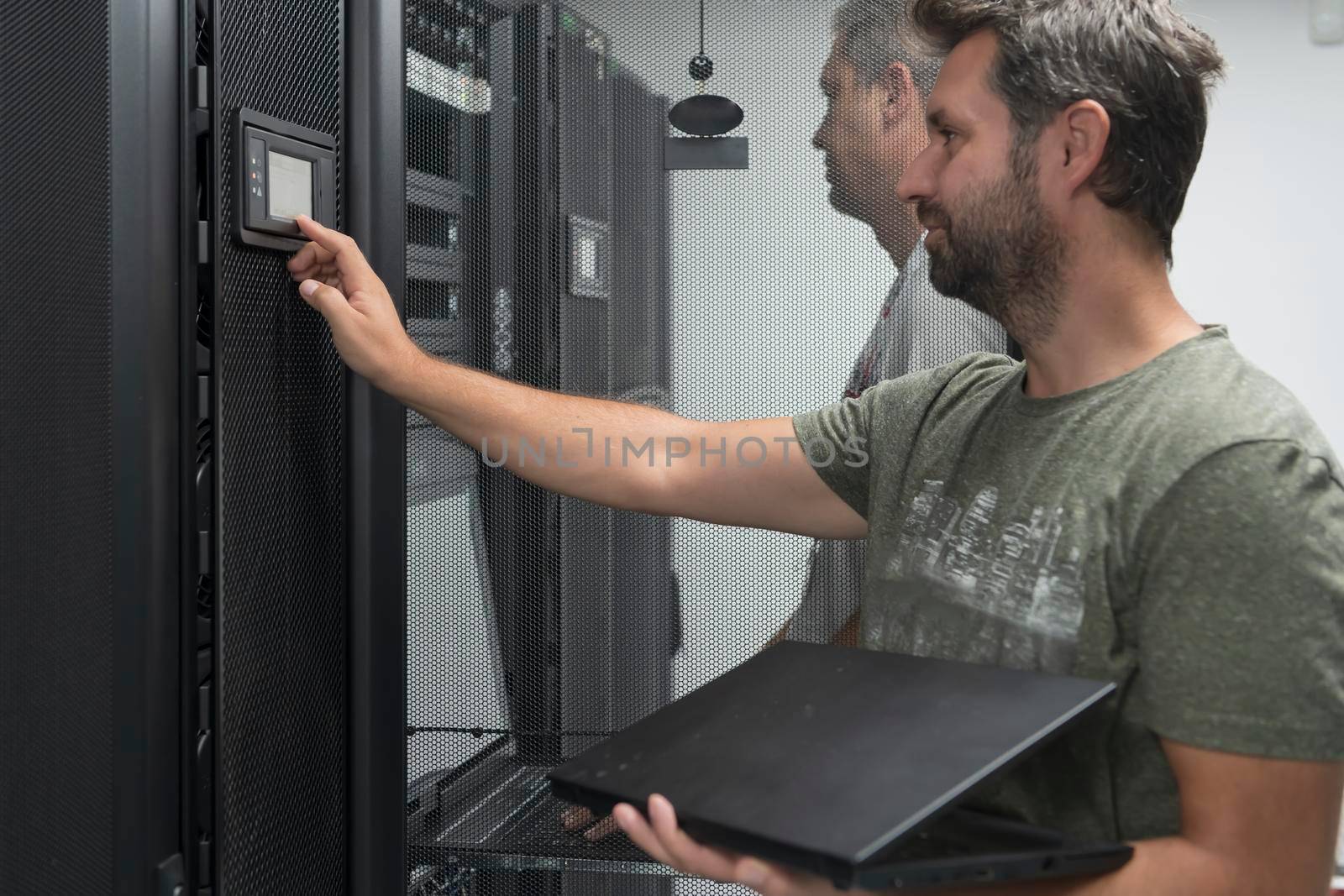 A couple of server engineers cooperate in high tech data centers. Technicians team updating hardware inspecting system performance in super computer server room or cryptocurrency mining farm.