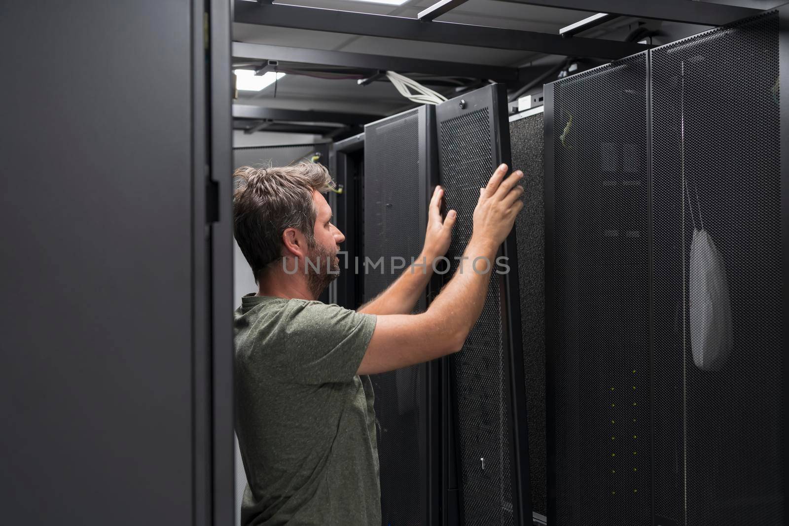 IT engineer working In the server room or data center. The technician puts in a rack a new server of corporate business mainframe supercomputer or cryptocurrency mining farm.
