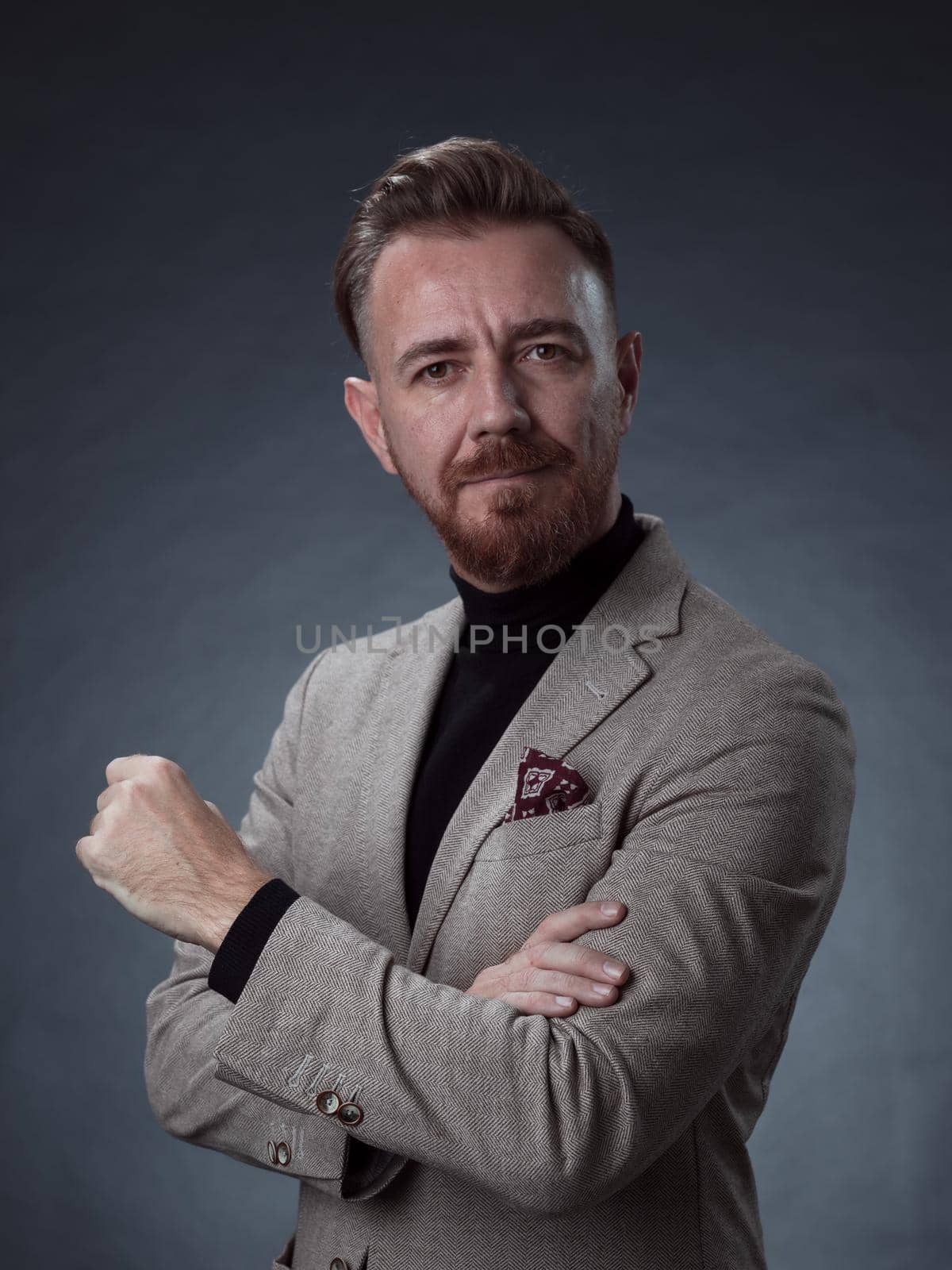 Portrait of a stylish elegant senior businessman with a beard and casual business clothes in photo studio isolated on dark background gesturing with hands. High quality photo