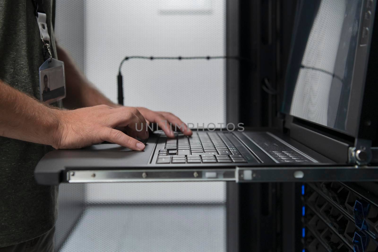 Close up on Data Center Engineer hands Using keyboard on a supercomputer Server Room Specialist Facility with Male System Administrator Working with Data Protection Network for Cyber Security. by dotshock