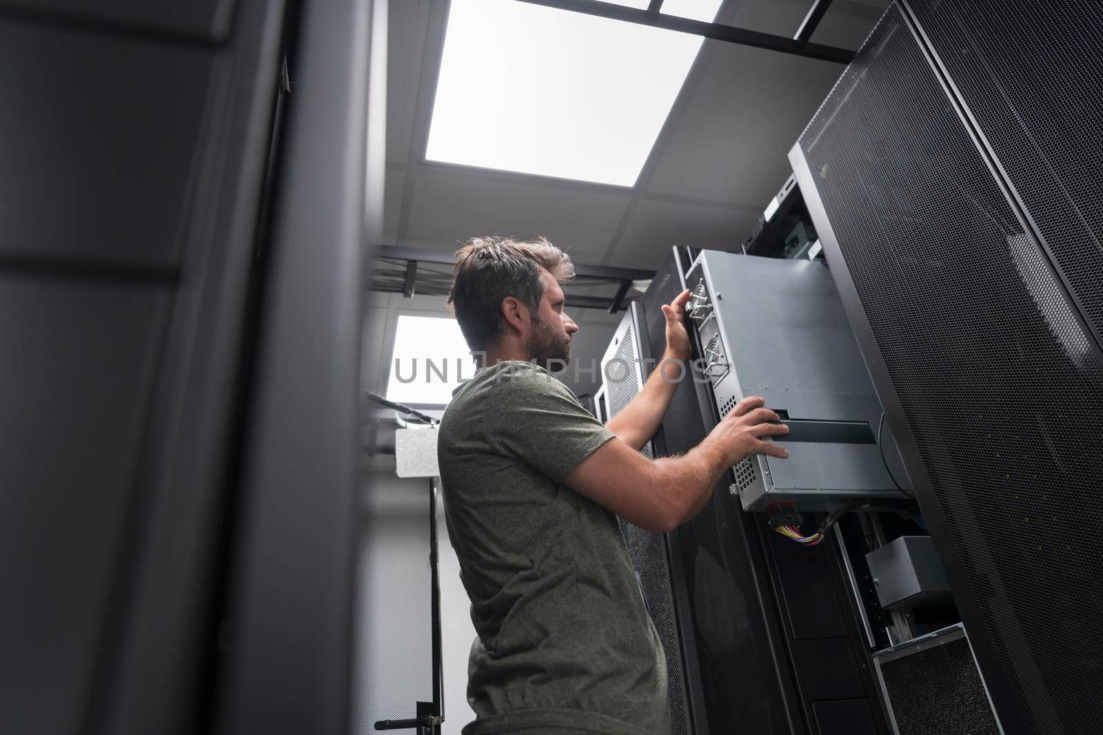 IT engineer working In the server room or data center. The technician puts in a rack a new server of corporate business mainframe supercomputer or cryptocurrency mining farm.