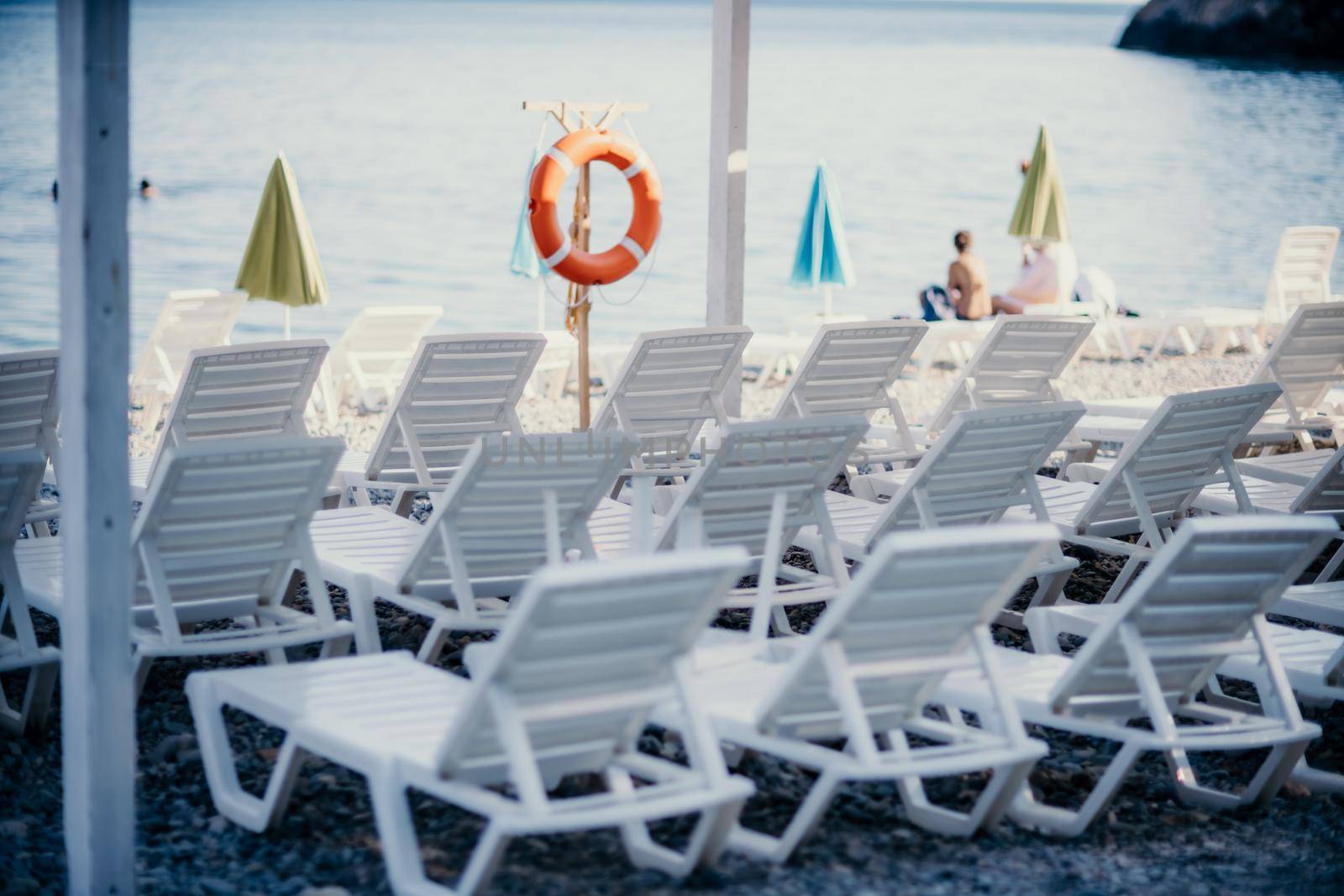 Several white sun loungers and an umbrella on a deserted beach. The perfect vacation concept