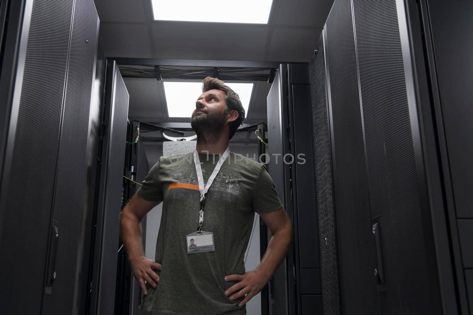 Portrait of male technician or network administrator standing brave as a hero with arms crossed in data center server room. by dotshock