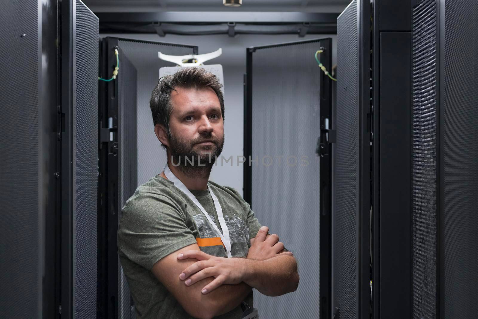 Portrait of male technician or network administrator standing brave as a hero with arms crossed in data center server room. High quality photo