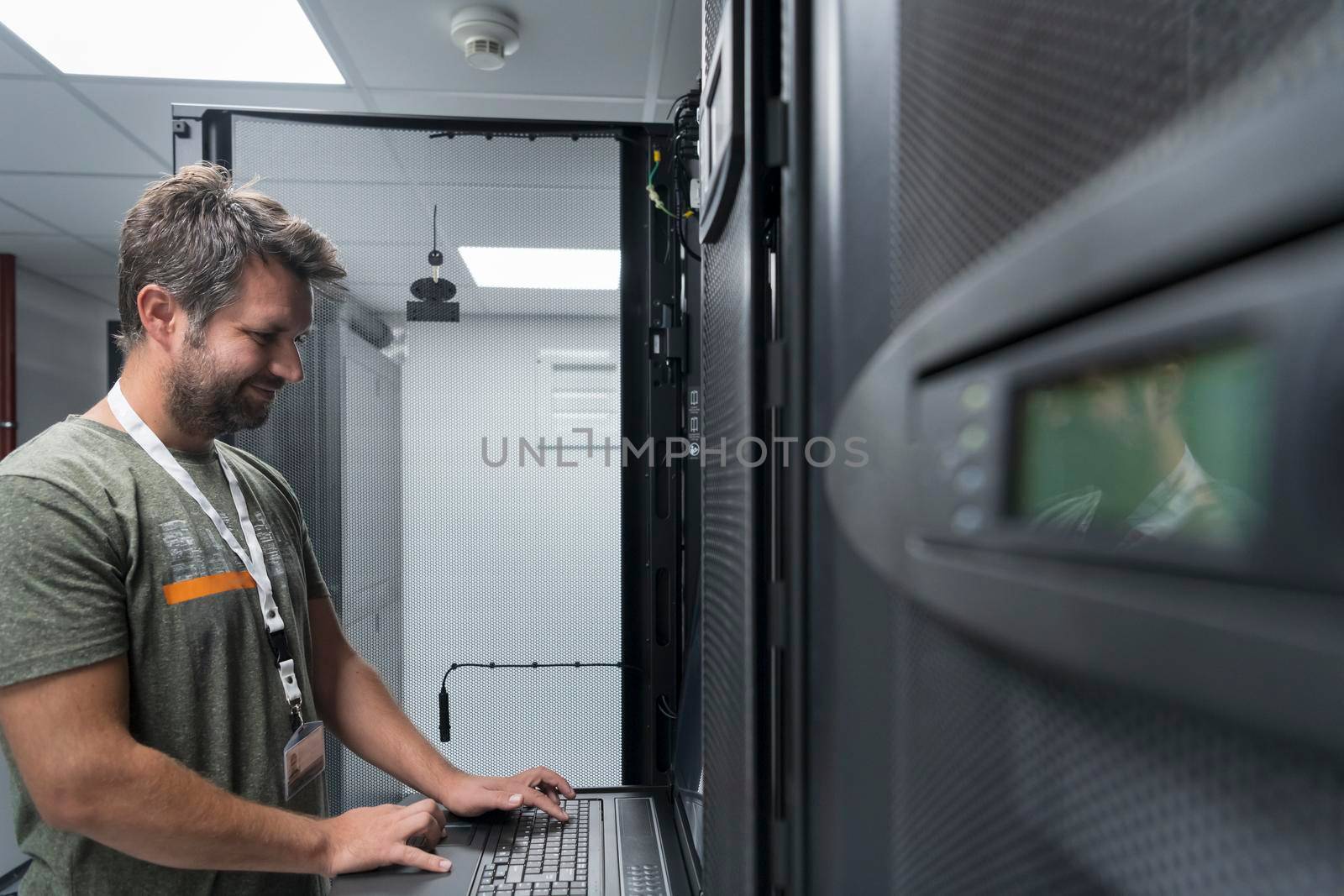 Data Center Engineer Usaing Keyboard on a Supercomputer. Server Room Specialist Facility with Male System Administrator Working with Data Protection Network for Cyber Security or Cryptocurrency Mining Farm