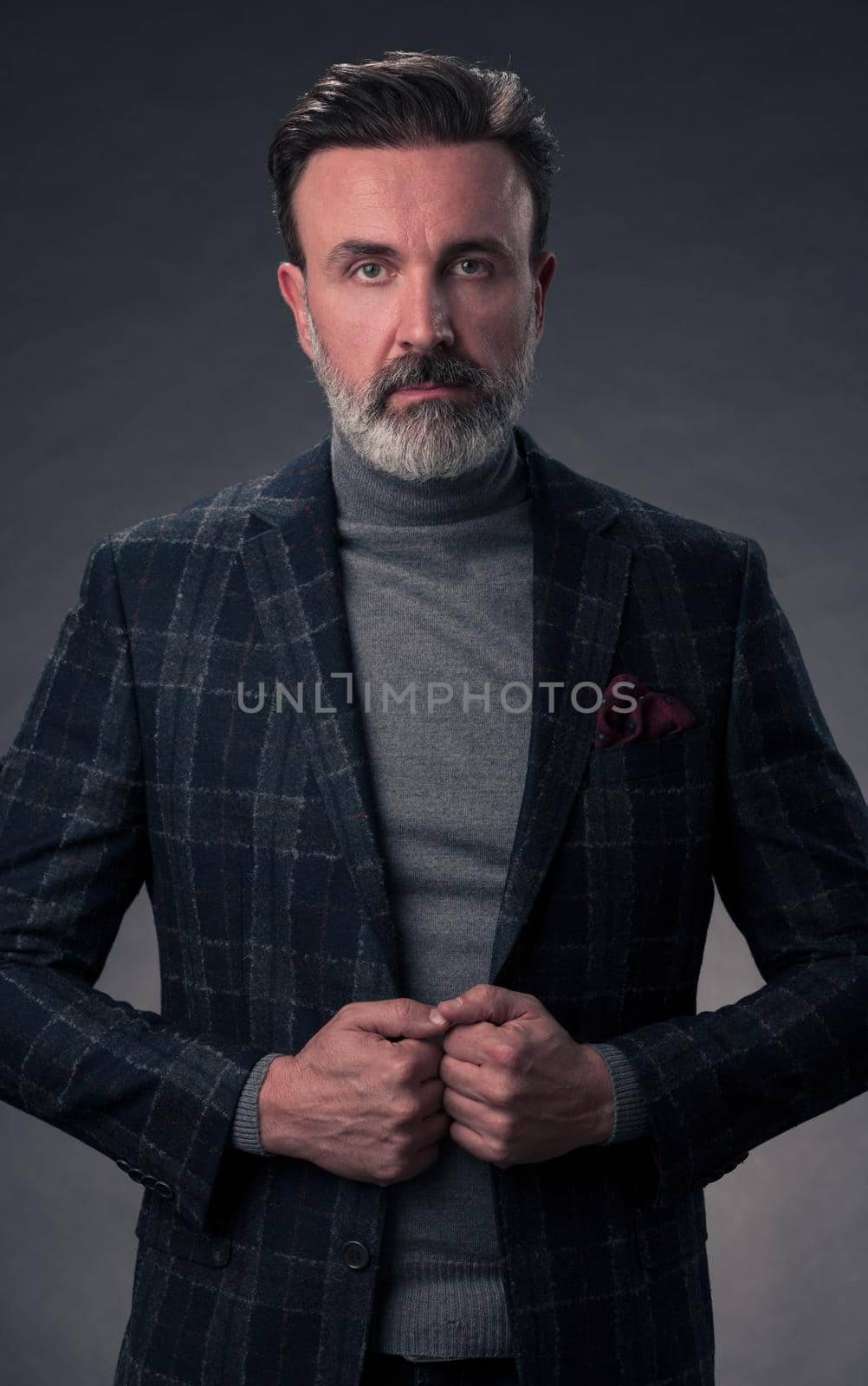 Portrait of a stylish elegant senior businessman with a beard and casual business clothes in photo studio adjusting suit by dotshock