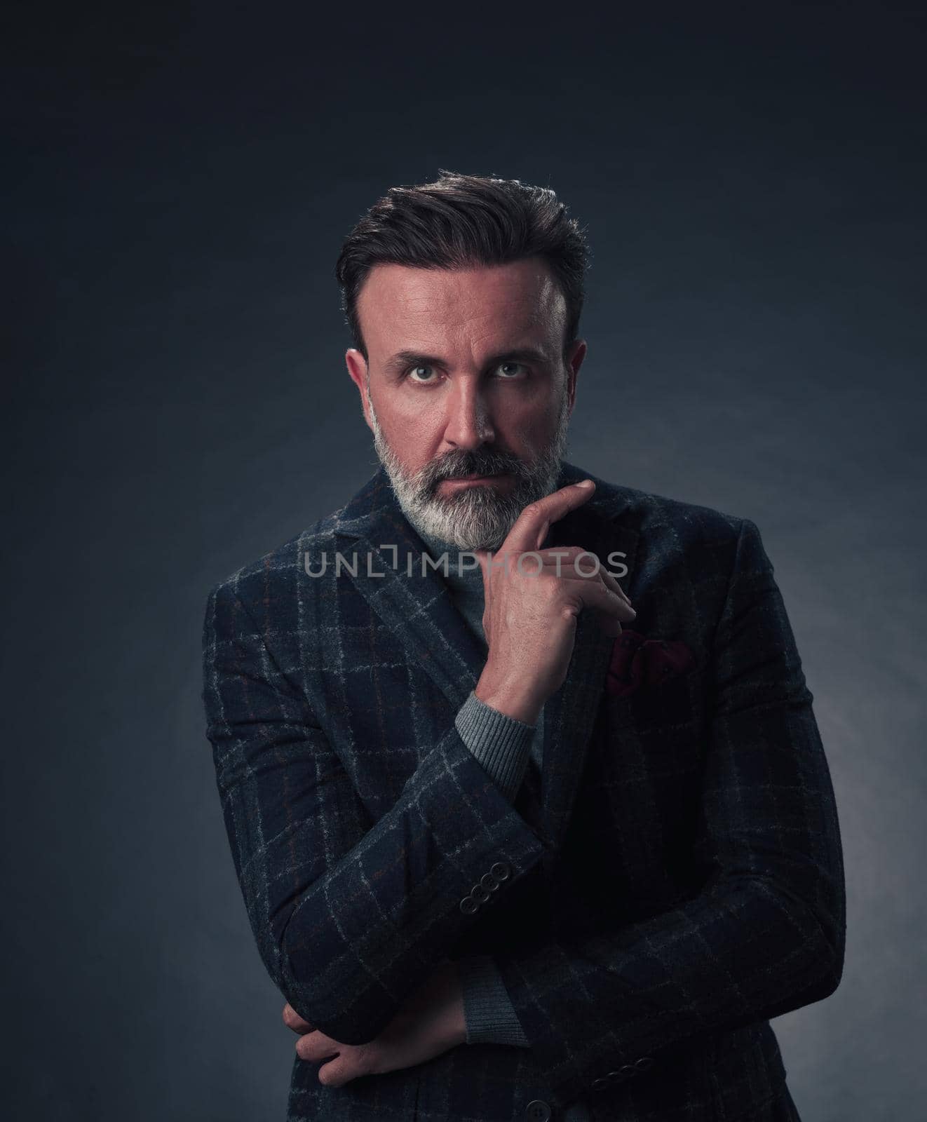 Portrait of a stylish elegant senior businessman with a beard and casual business clothes in photo studio isolated on dark background gesturing with hands by dotshock