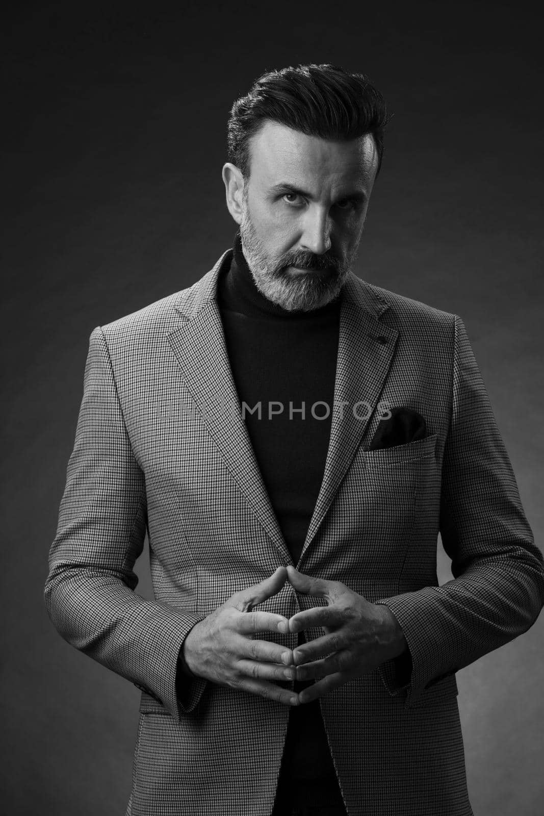 Portrait of a stylish elegant senior businessman with a beard and casual business clothes in photo studio isolated on dark background gesturing with hands by dotshock