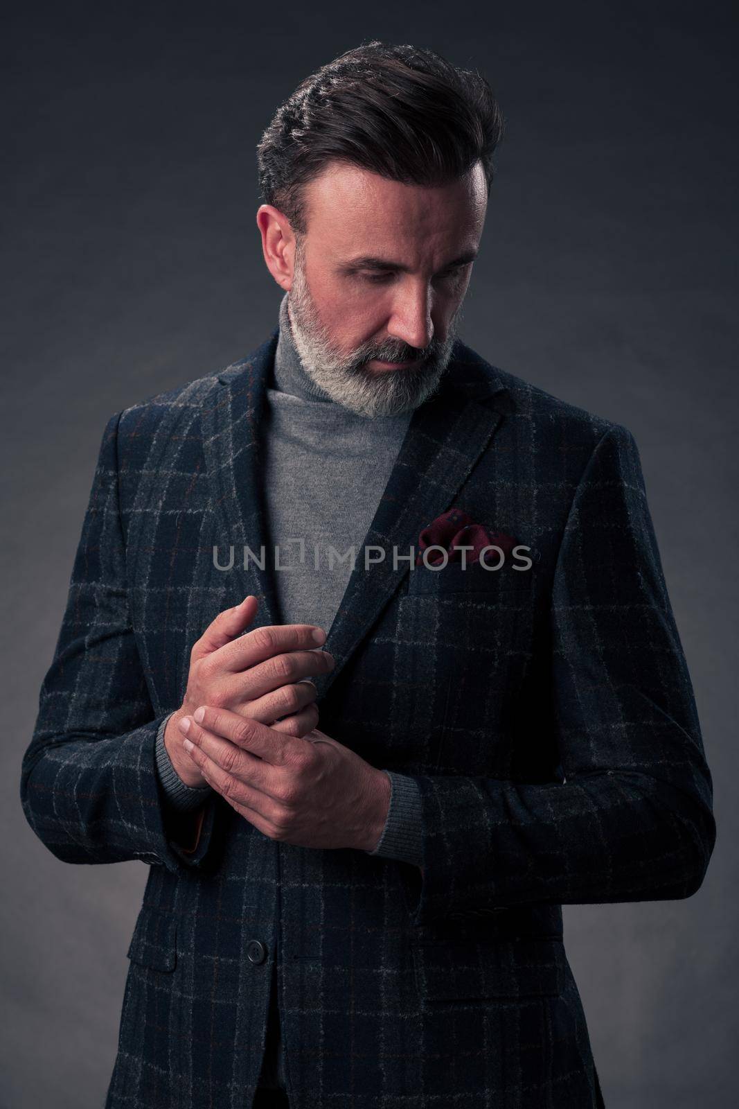 Portrait of a stylish elegant senior businessman with a beard and casual business clothes in photo studio isolated on dark background gesturing with hands by dotshock