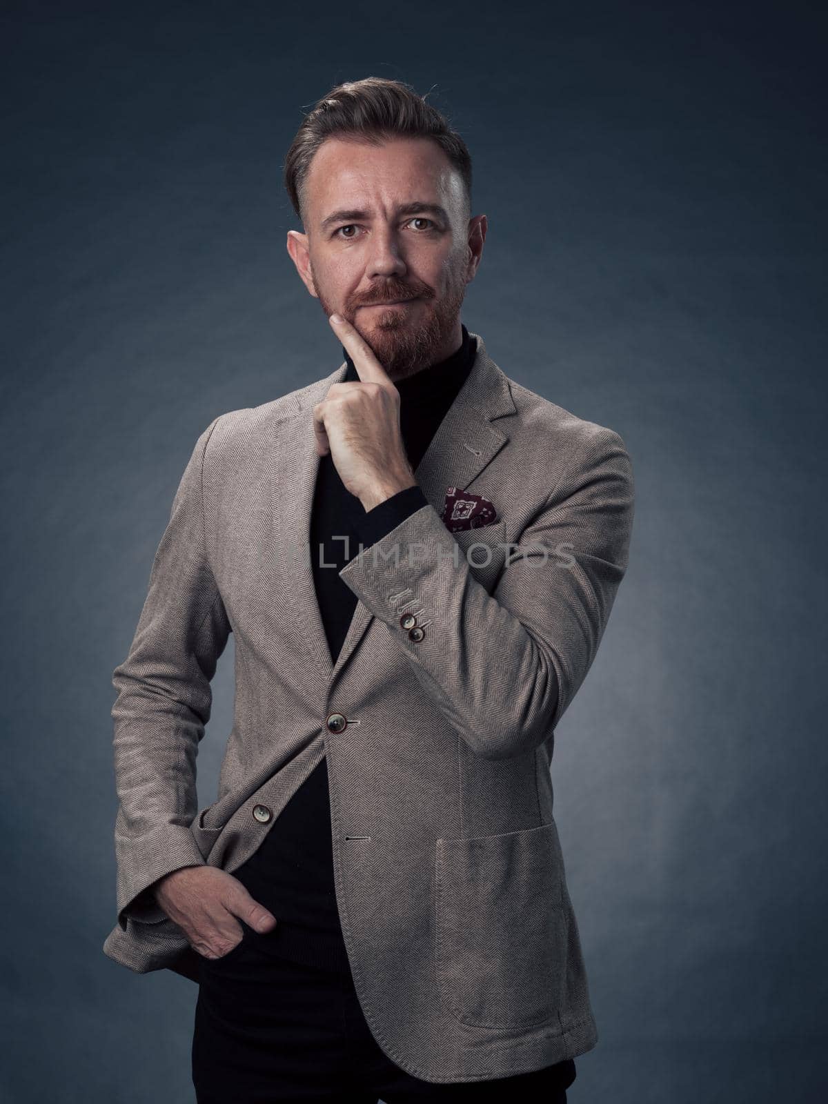 Portrait of a stylish elegant senior businessman with a beard and casual business clothes in photo studio isolated on dark background gesturing with hands by dotshock