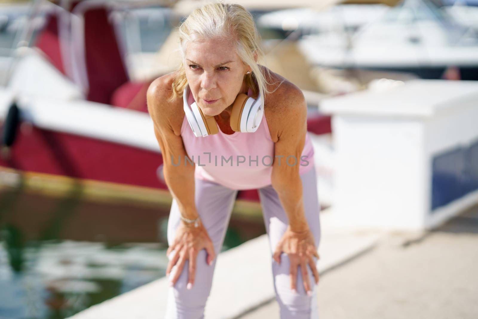 Mature sportswoman stretching her arms after exercise. Concept of healthy living in the elderly. Senior woman in fitness clothing. Older female doing sport to keep fit.