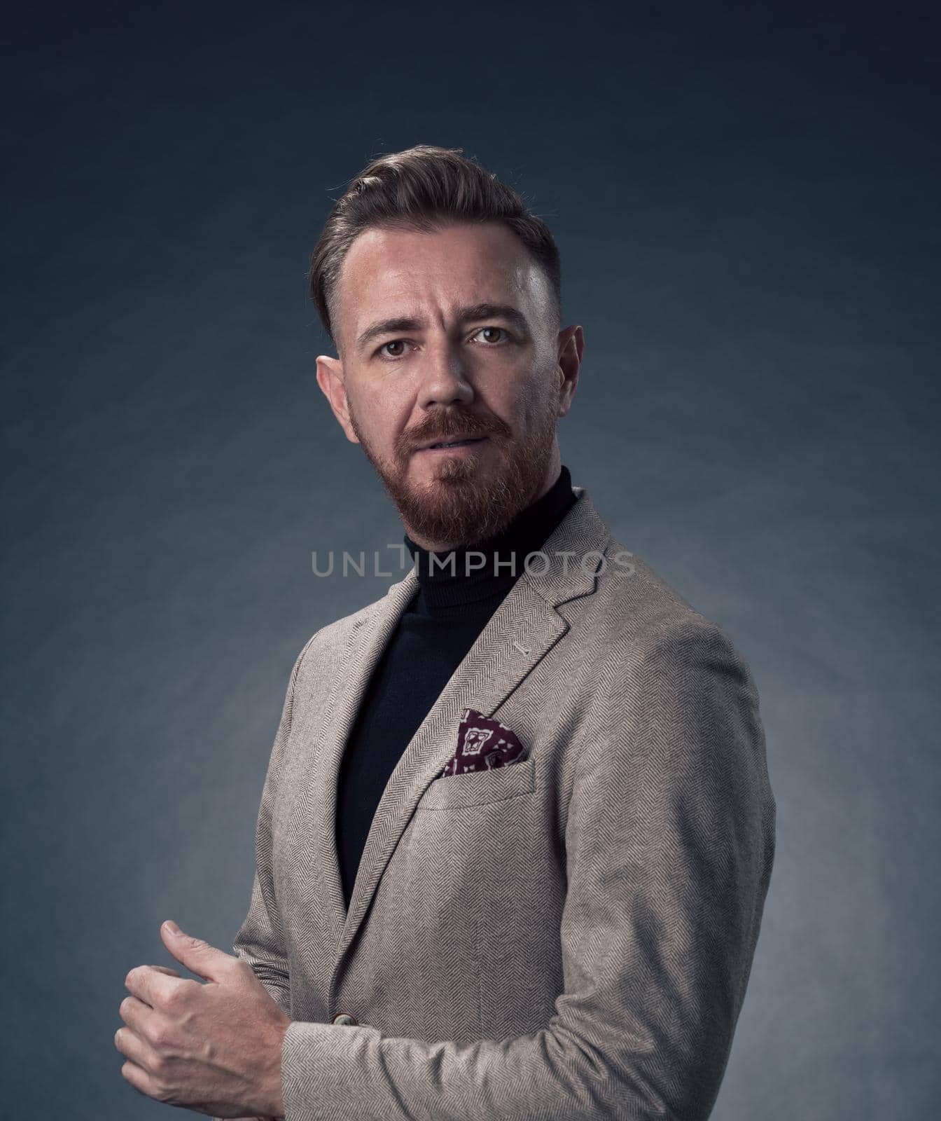 Portrait of a stylish elegant senior businessman with a beard and casual business clothes in photo studio isolated on dark background gesturing with hands. High quality photo