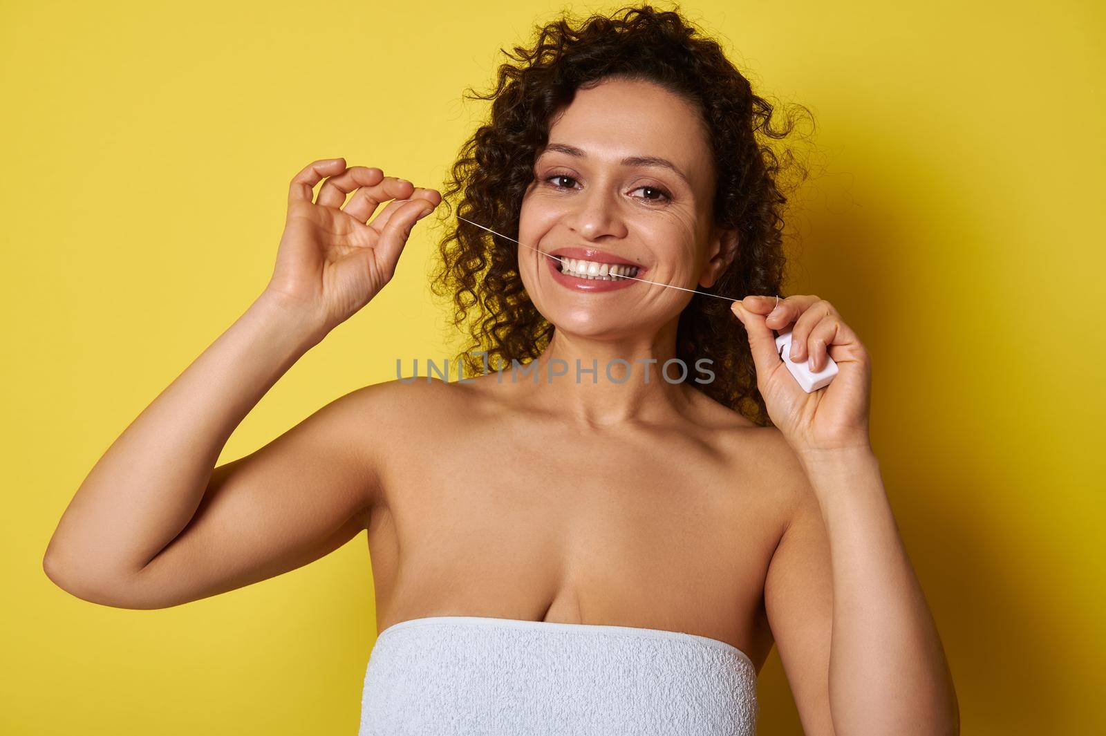 Smiling young woman taking care about her teeth by using a dental floss for cleaning dental cavity by artgf