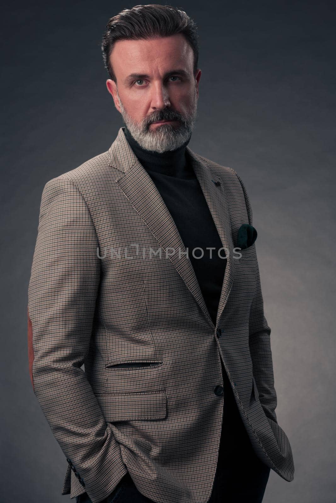 Portrait of a stylish elegant senior businessman with a beard and casual business clothes in photo studio isolated on dark background gesturing with hands by dotshock