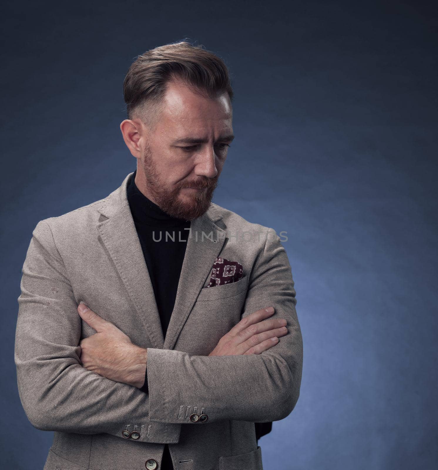 Portrait of a stylish elegant senior businessman with a beard and casual business clothes in photo studio isolated on dark background gesturing with hands. High quality photo