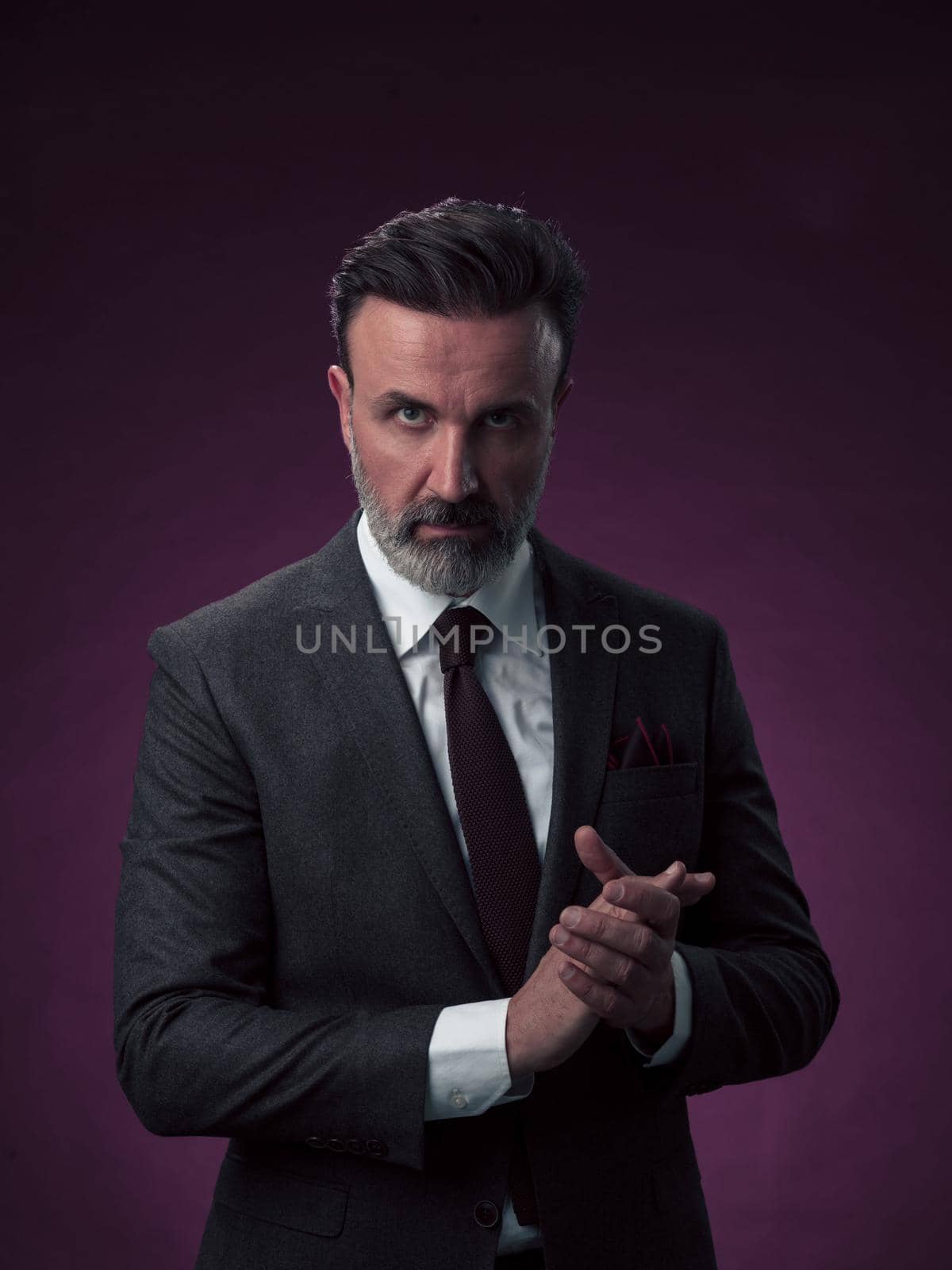 Portrait of a stylish elegant senior businessman with a beard and casual business clothes in photo studio isolated on dark background gesturing with hands by dotshock