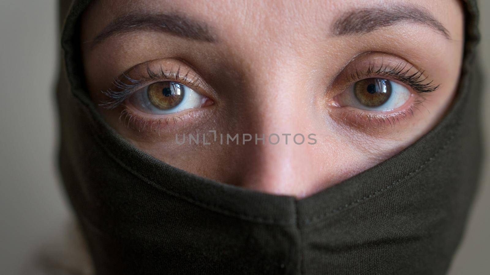 Female portrait of young girl wearing khaki balaclava, only eyes are visible, mandatory conscription, military, feminism, equality concept by balinska_lv