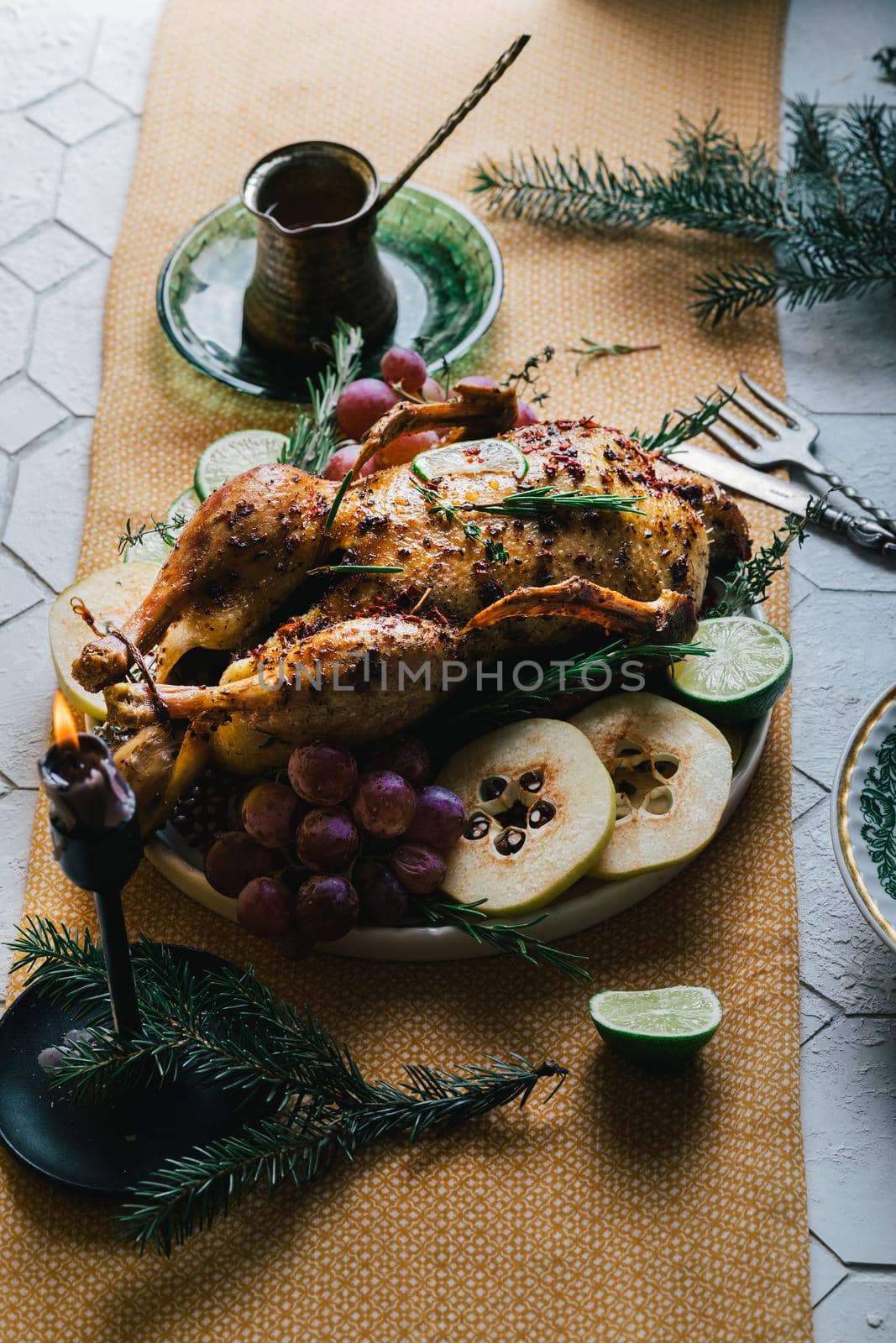 A duck baked for Thanksgiving as a symbol of family unification at a common holiday table. Still life in orange tones, shot in a light key on a white ceramic background. The atmosphere of the festival and celebration. The dish is decorated with grapes, lime, quince and aromatic herbs.