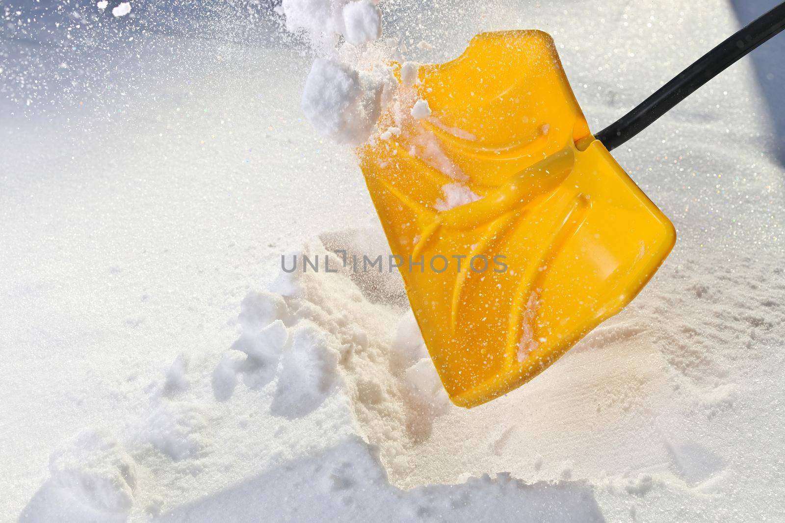 Yellow Snow Shovel Shoveling Fresh, Deep Powdery Snow on a Sunny day to Clear a Path or Driveway. High quality photo