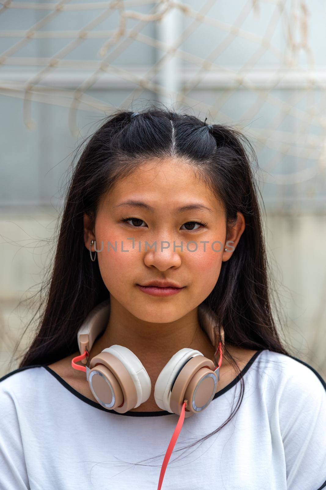 Vertical portrait of Asian teen girl looking at camera. by Hoverstock