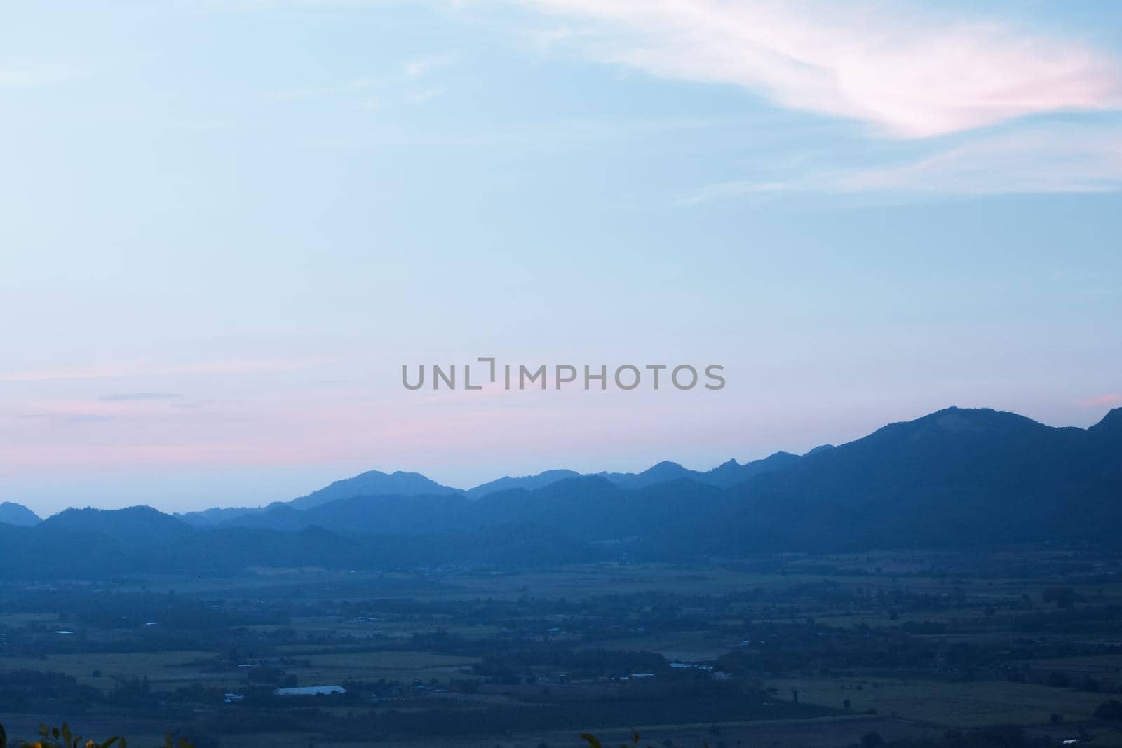 The landscape of green rice fields with the evening light of the sun contrasting with the sky.