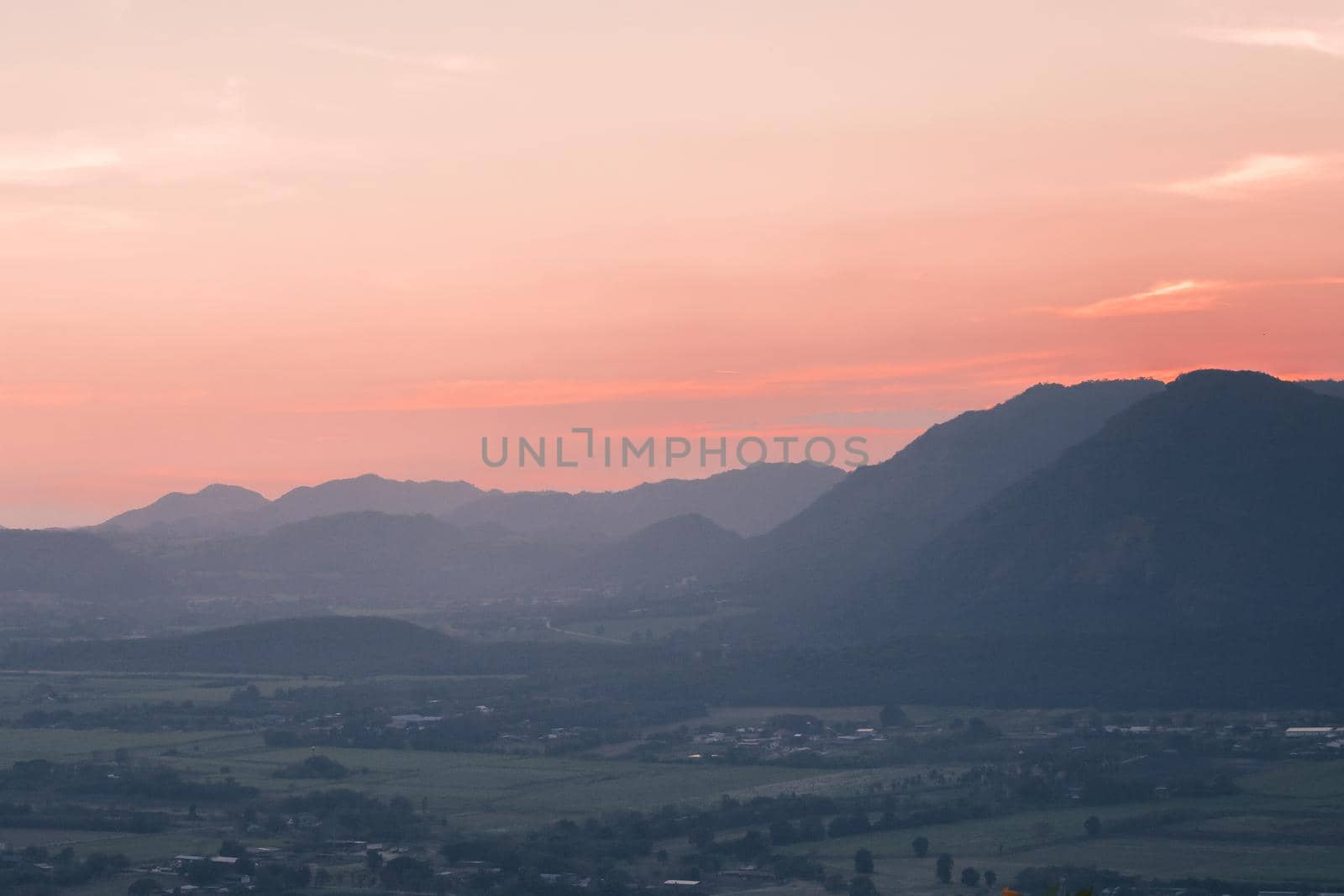 The landscape of green rice fields with the evening light of the sun contrasting with the sky.