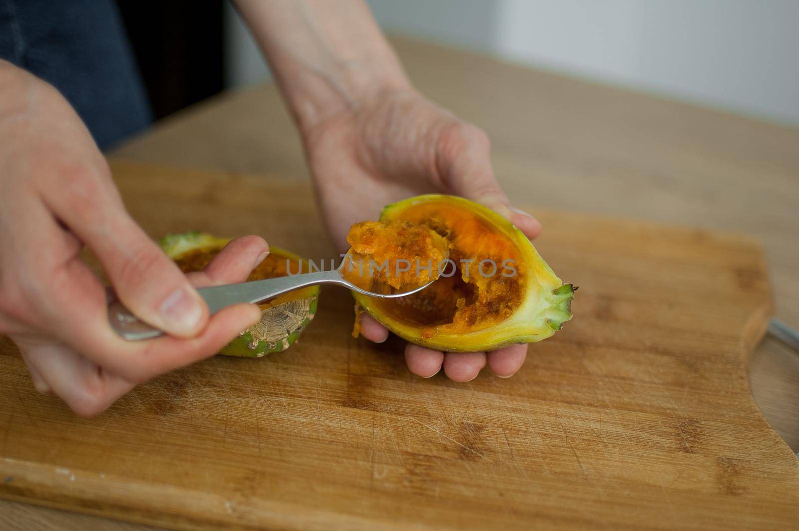 Female eats fresh organic ripe cactus pear or opuntia with a spoon. Exotic fruits, healthy eating concept.