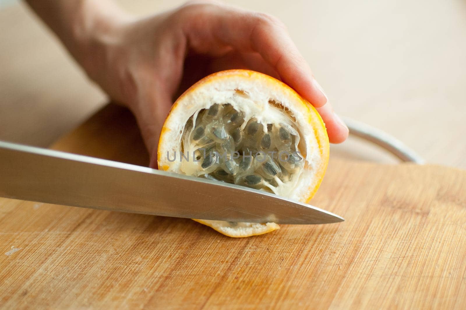 Fresh organic ripe granadilla or yellow passion fruit cut in half on a wooden board. Exotic fruits, healthy eating concept by balinska_lv