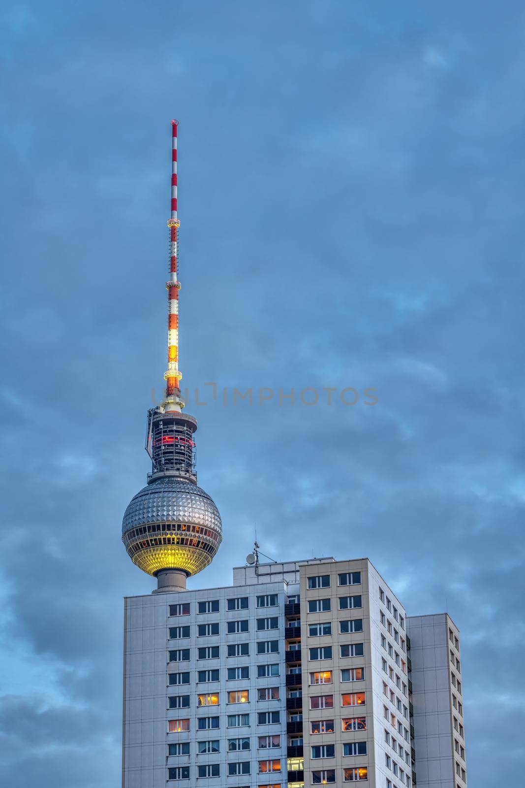 The famous TV Tower of Berlin at dusk with a typical GDR prefabricated apartment building